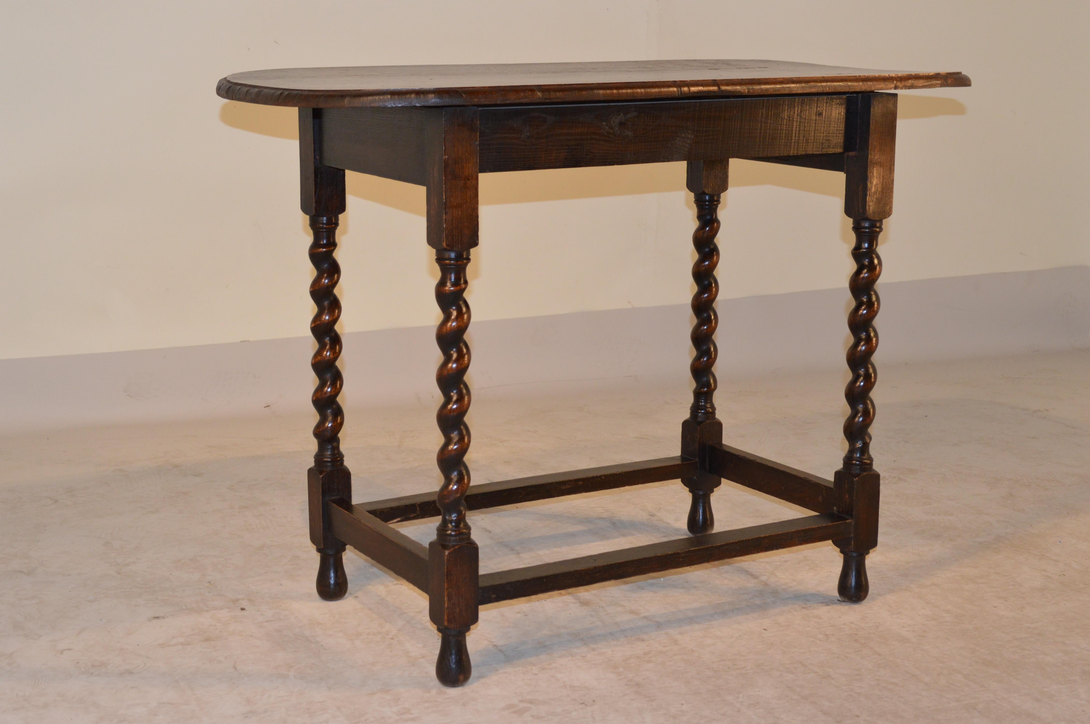 19th century English oak side table. The oval top has a hand-beveled edge and follows down to an apron connected to hand-turned barley-twist legs joined by stretchers. Raised on hand-turned feet.
  