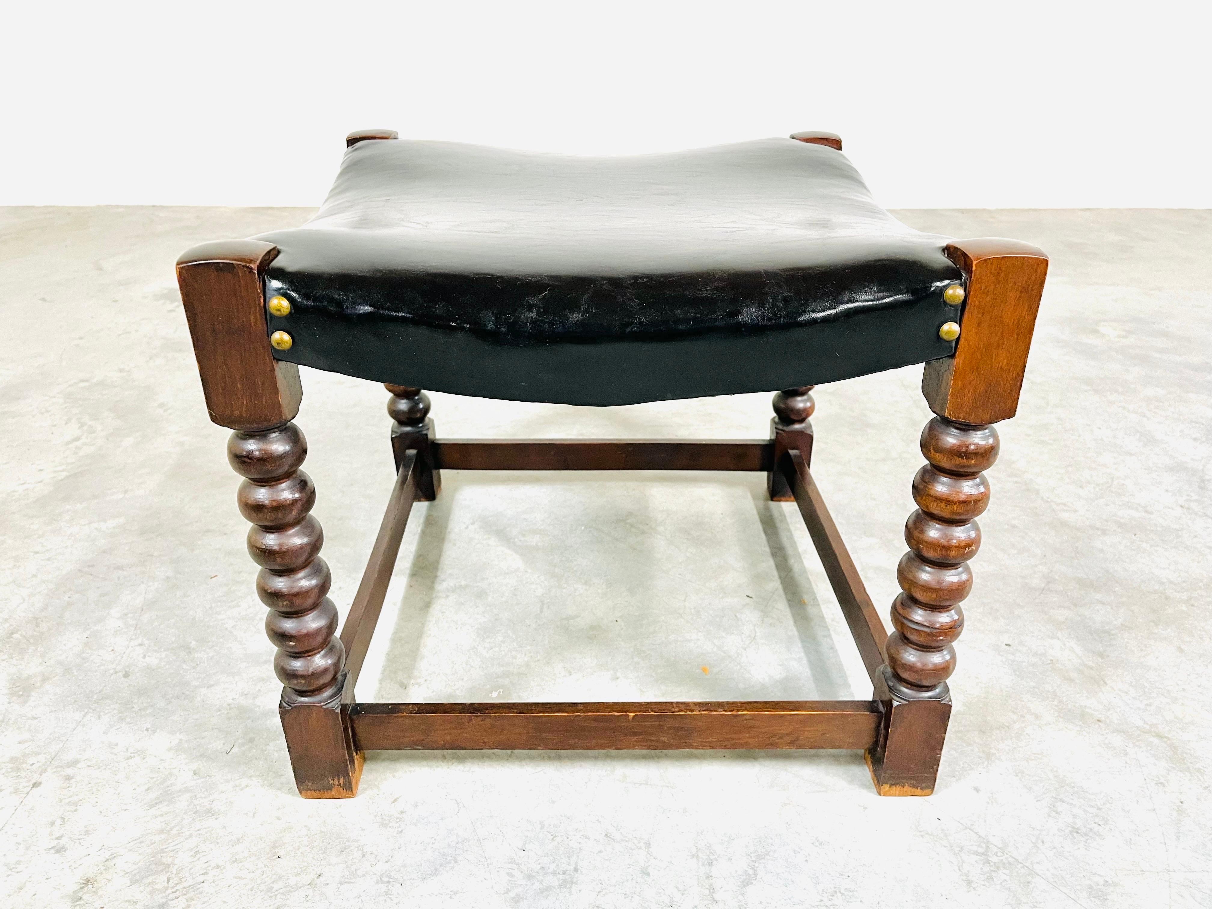 A beautifully hand carved 19th century Jacobean stool having oak frame with soft black leather top adorned with brass buttons. 
In very nice vintage condition having solid frame with well maintained leather. 
Measures: 16 x 18.75 x 18.75” HWD SH