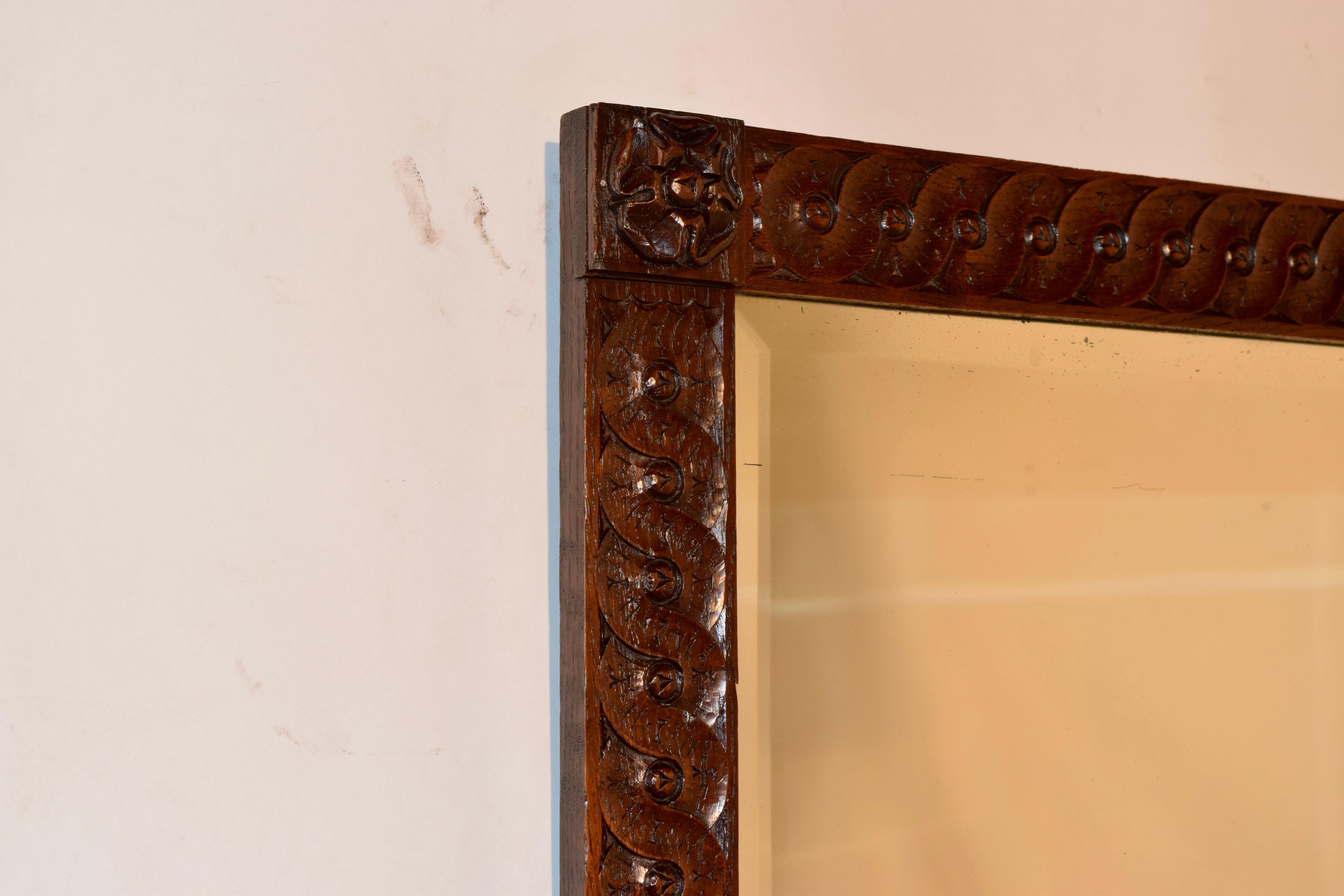 19th century oak hand carved mirror from England with Tudor rose carvings at all four corners of the frame surrounded by hand carved framing. Original beveled mirror with wear to mercury glass.