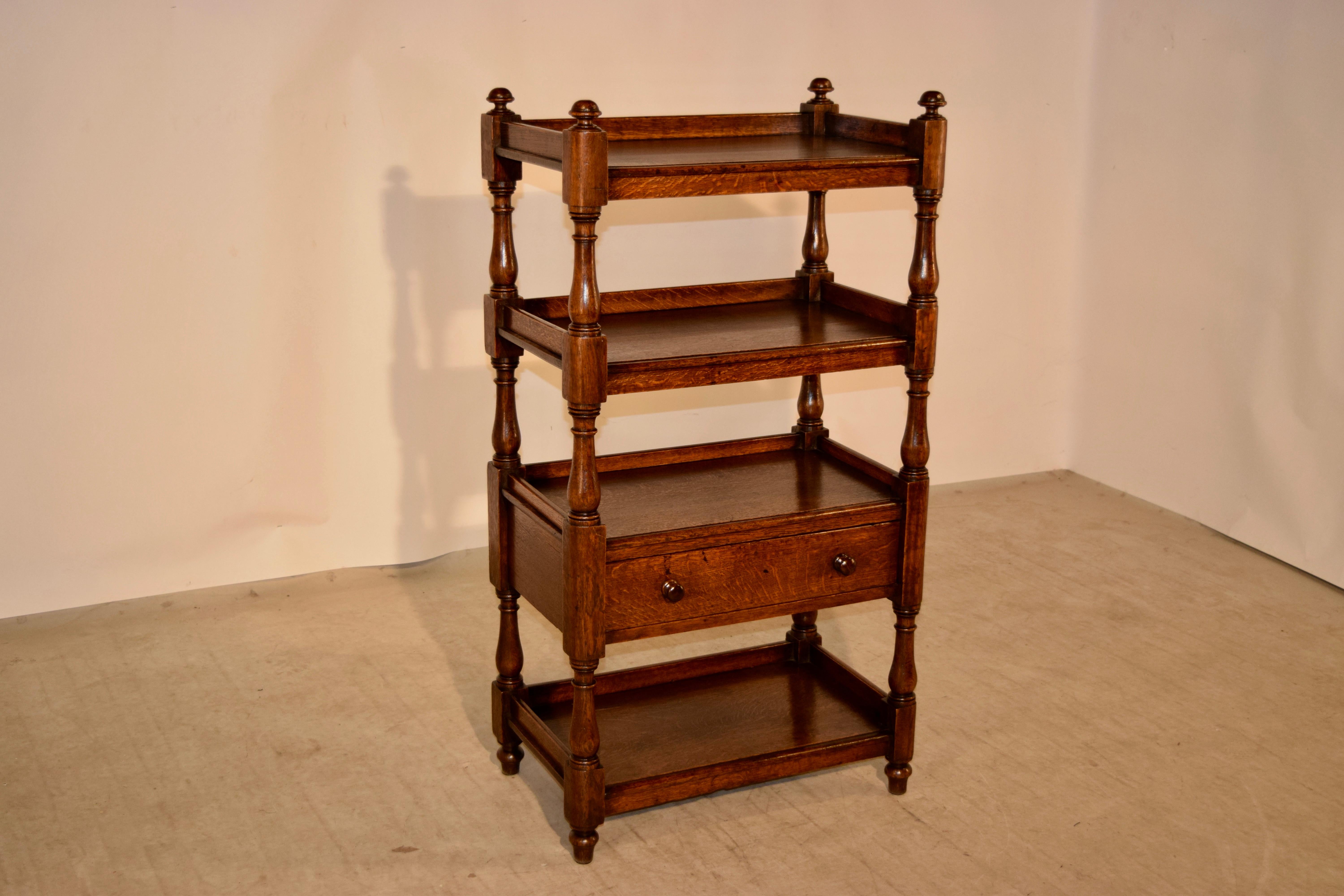 19th century oak shelf from England with finials decorating the top, following down to four shelves, all with galleries and hand turned shelf supports. Beneath the third shelf is a single drawer. Raised on hand turned feet.
