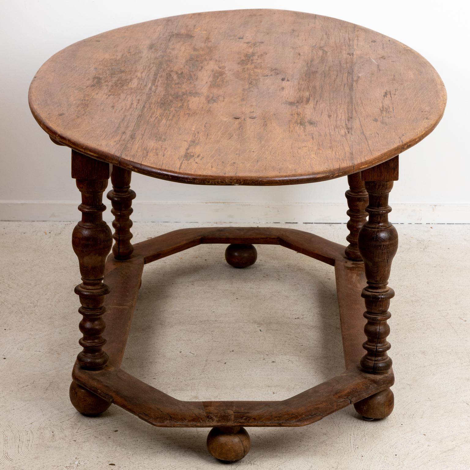 Circa 19th century English oak oval table with bottom stretcher and vase-and-ring turned legs on bun feet. Please note of wear consistent with age including minor wood loss, patina, and finish loss due to antique age.