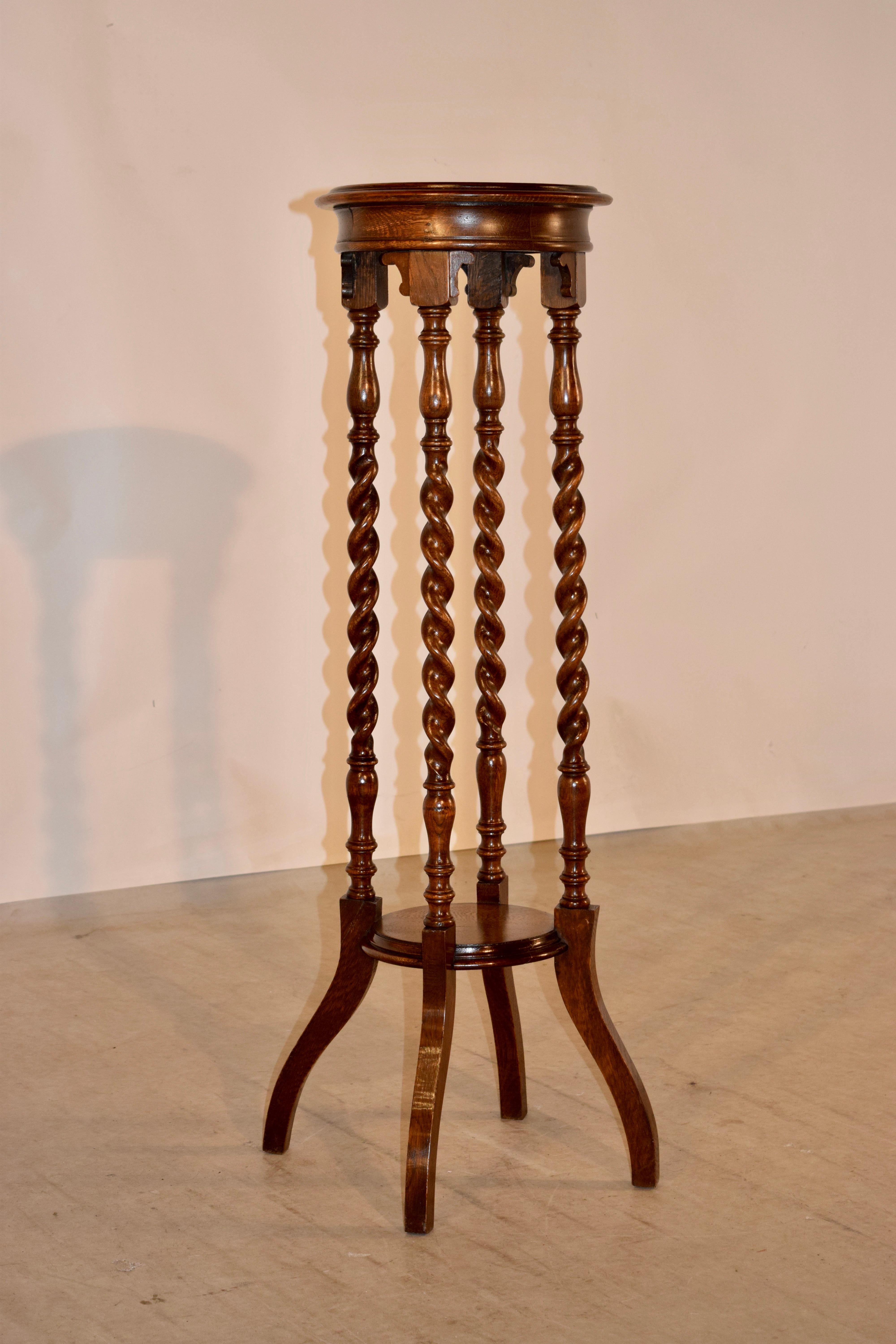 19th century oak plant stand from England with a dish shaped top which measures 10.75 inches x 9.88 inches, and is supported on hand tuned barley twist legs, ending in broadly splayed feet, joined by a lower shelf, which has a molded and beveled