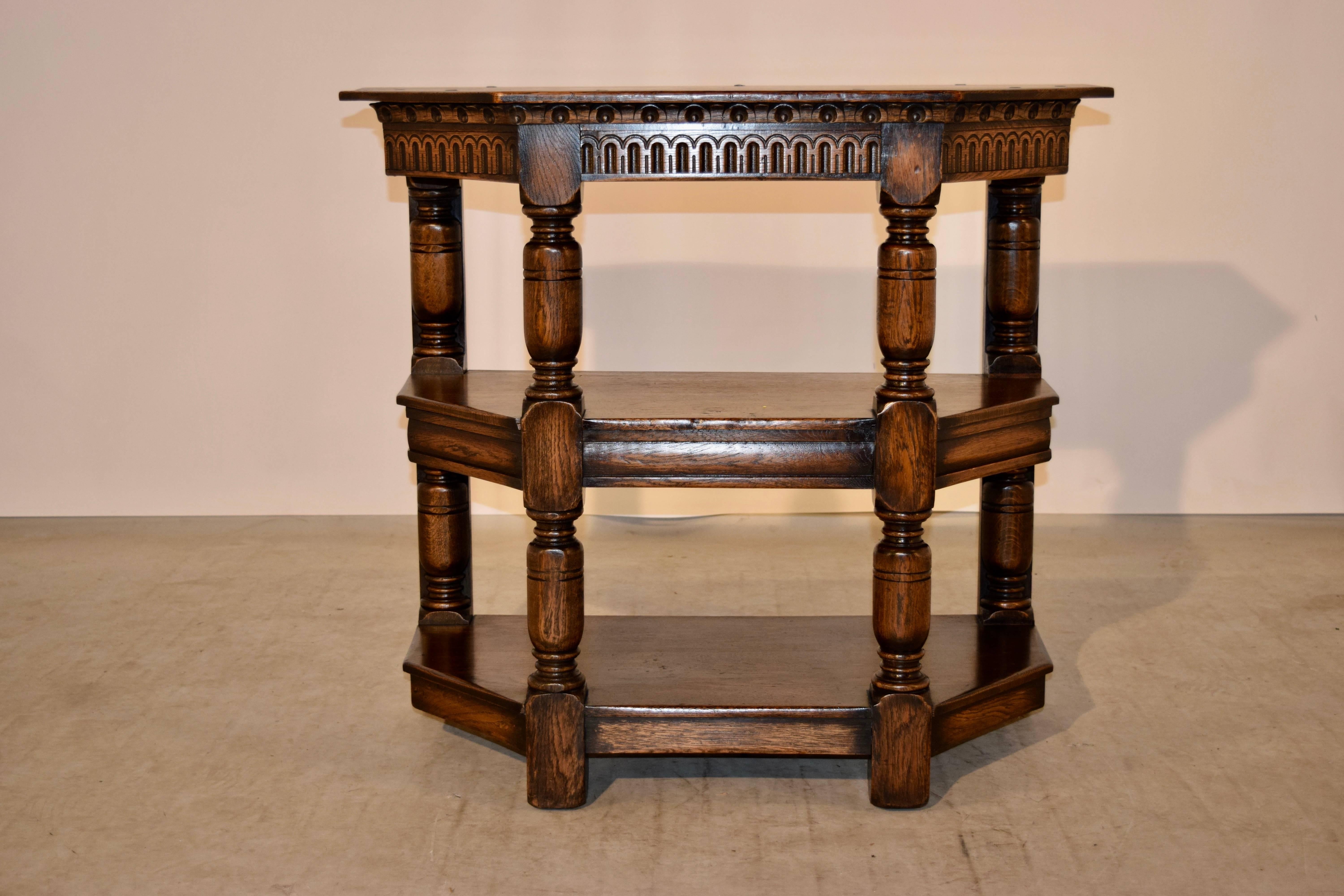 19th century English shelf made of oak. The top is shaped and has pegged construction, following down to a base with hand-carved decorated molding and apron over two shelves joined by hand-turned legs in the front and simple legs in the back for