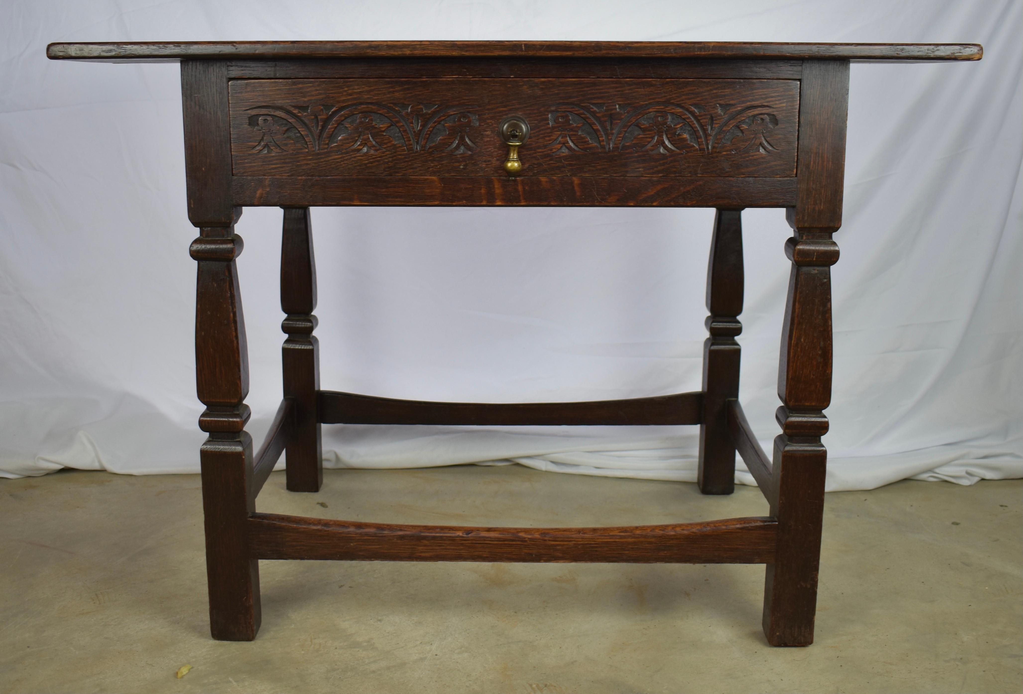 Oak side table built in England in the late 1800s in the William and Mary style using dovetail construction. The table is rectangular in shape and features a large single drawer on the front, delicately decorated with symmetrically hand-carved