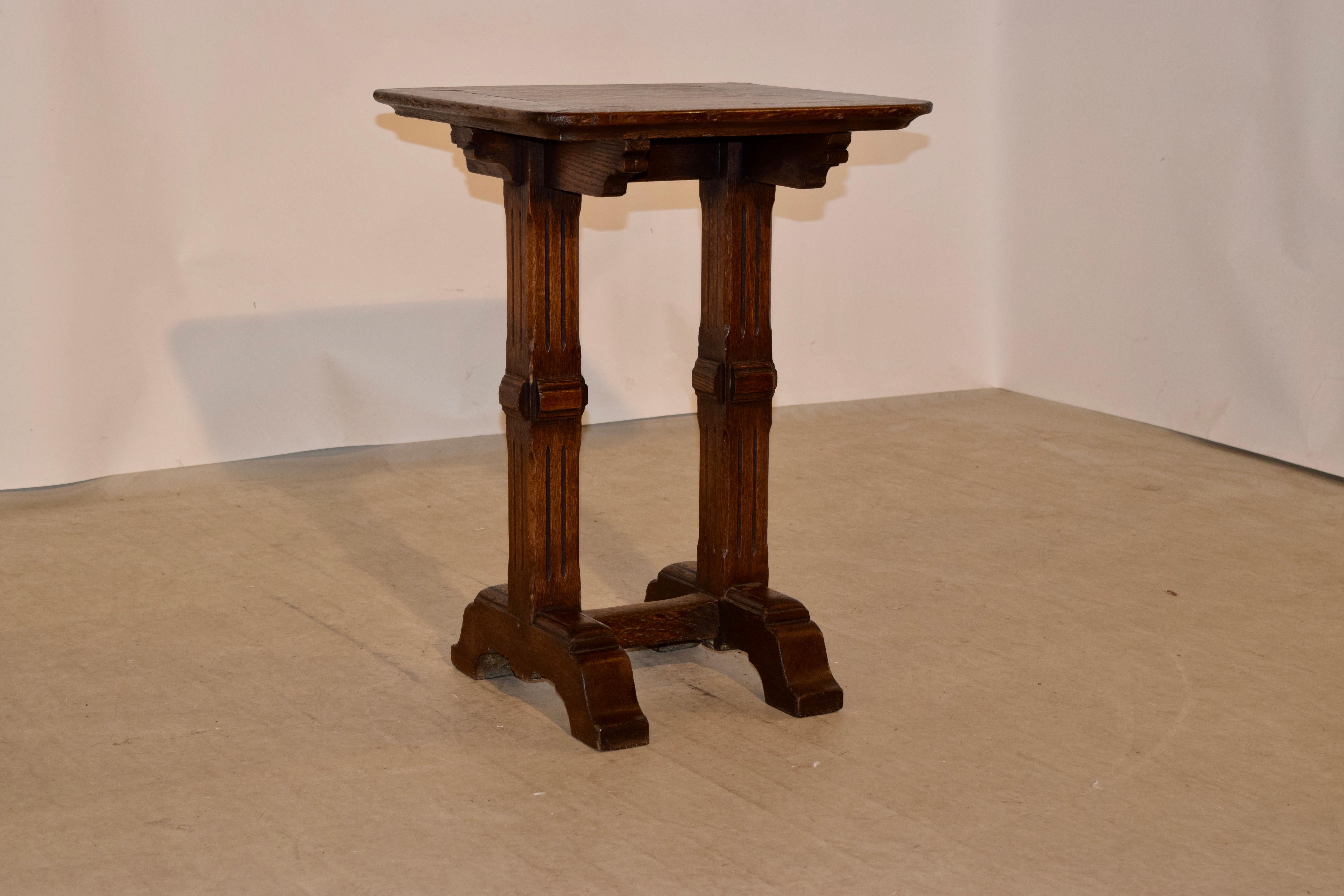 19th Century oak side table from England with a banded top and scalloped brackets over hand carved reeded legs, supported on bracket feet which are joined by a single stretcher.