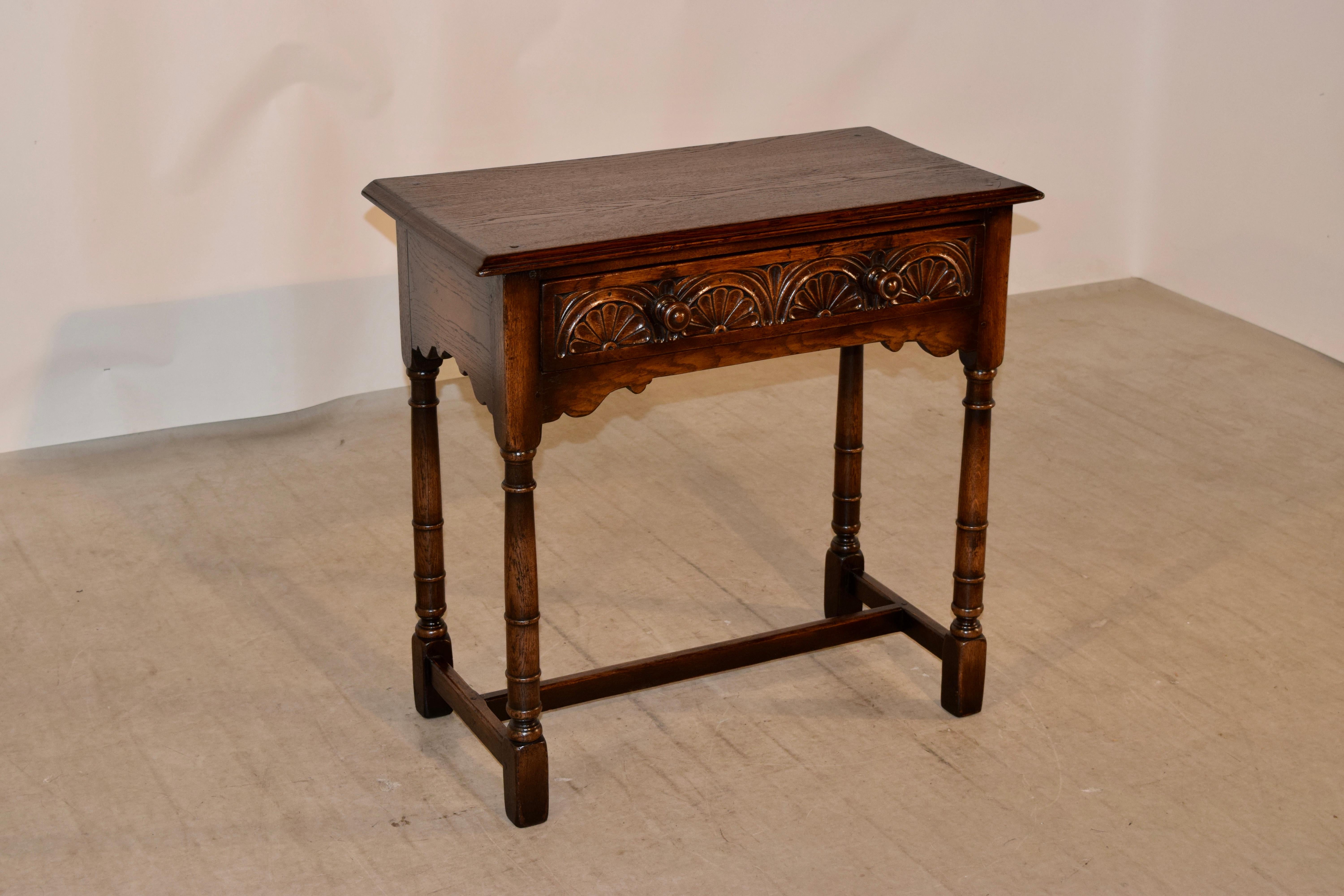 Late 19th century oak side table from England with a beveled edge around the top, following down to simple sides with wonderfully hand scalloped aprons and a single drawer in the front with lovely hand carved decoration. Supported on hand turned