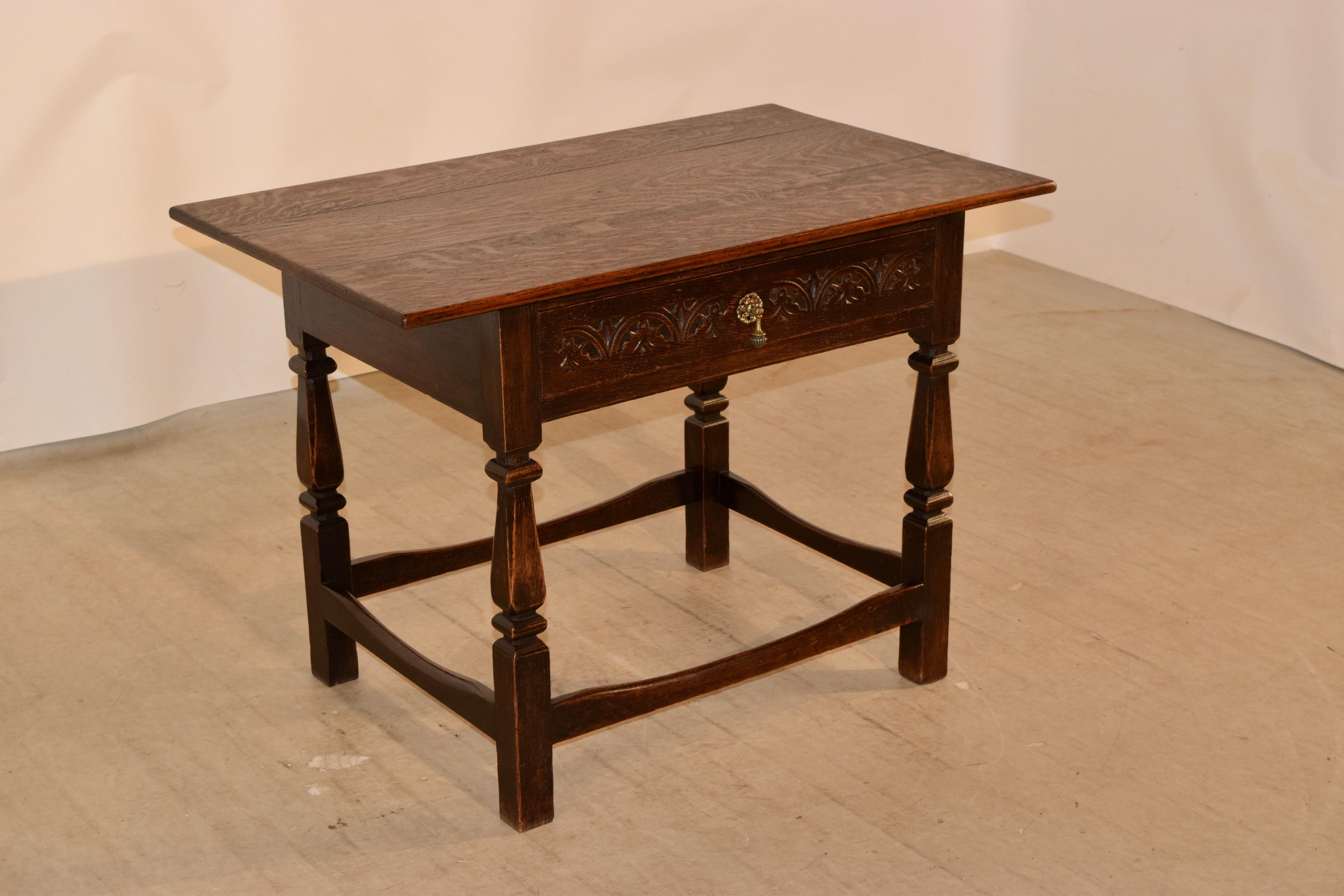 19th century oak side table from England with a three plank top, following down to a simple apron, containing a single drawer in the front with a hand carved decorated drawer front. The legs are hand-turned and are a very unusual squared off turned