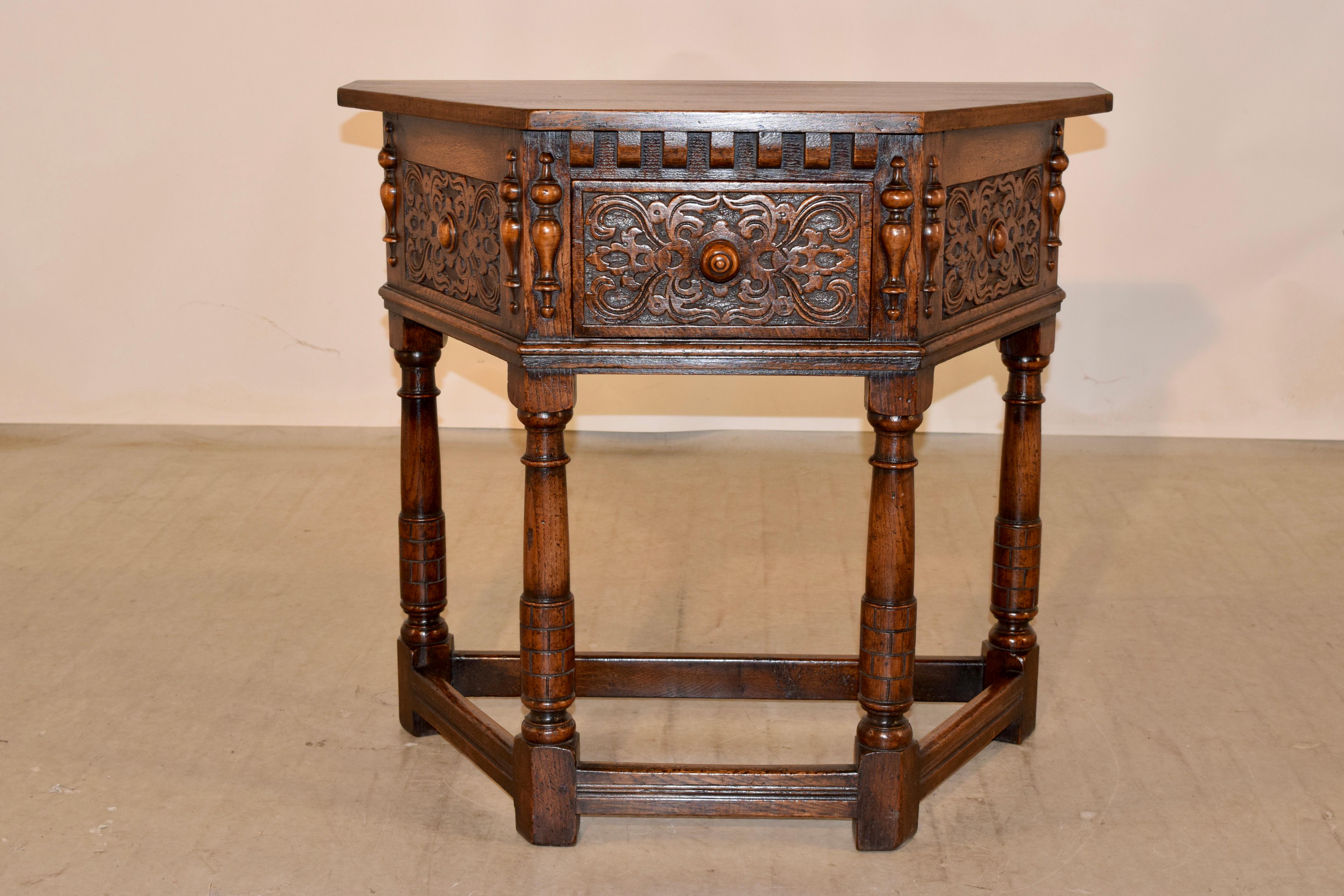 19th Century English oak side table with a five-sided top following down to sides with split moldings flanking carved panels and a single drawer with a carved drawer front, also flanked by split moldings. The piece is supported on hand turned legs,