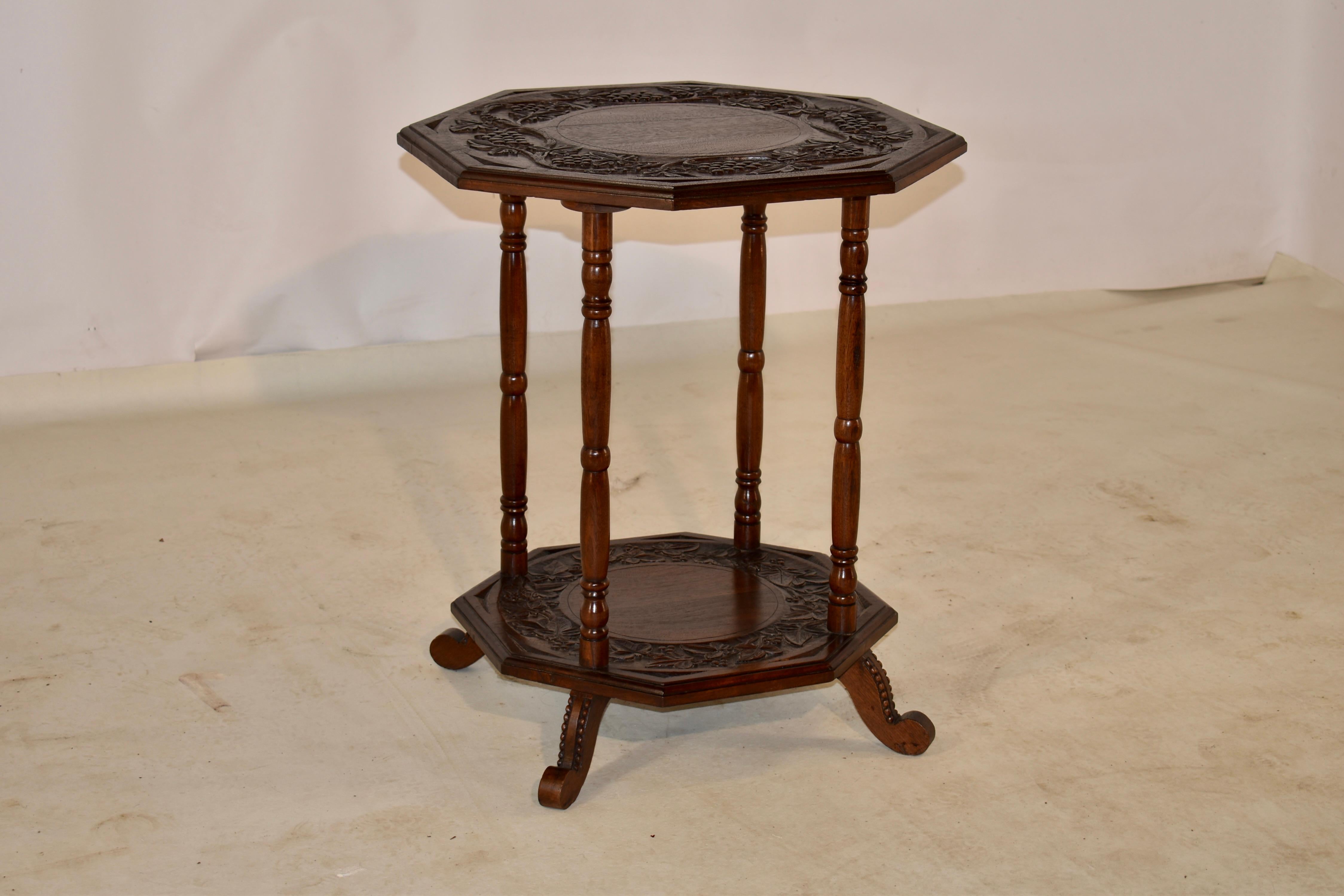19th century oak side table from England with an octagonal shaped top with a carved decorated band and beveled edge over four turned legs, joined by a lower shelf, which mirrors the top of the table. The table is supported on hand shaped feet, which