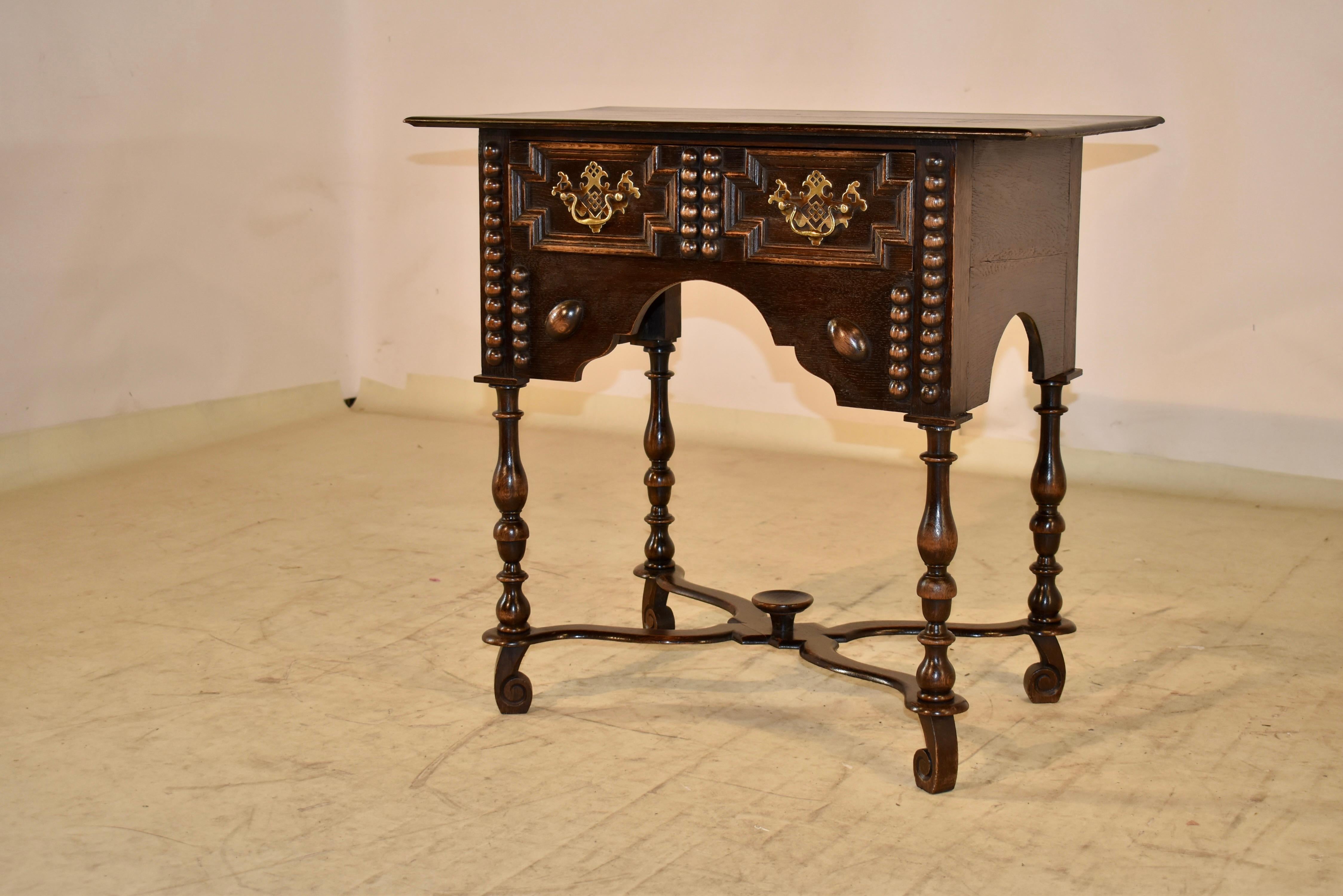 19th century Oak side table from England with a simple edge around the top, following down to simple sides and a single drawer in the front. The drawer front has raised decorative paneling and applied beaded decoration, and is flanked by additional