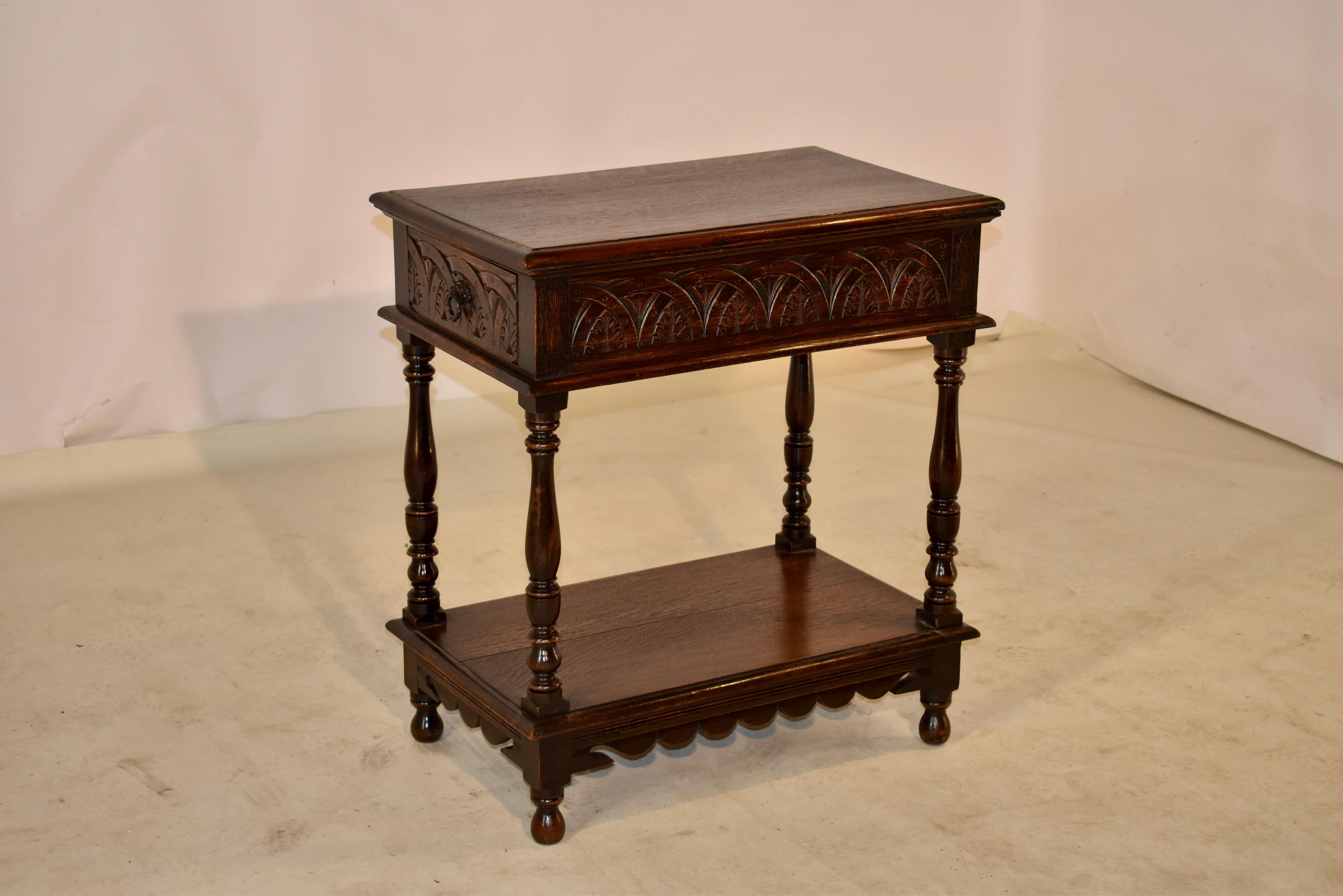 19th century oak side table from England with a beveled edge around the top, following down to a wonderfully carved apron which contains a single drawer on one end of the table. The apron is carved on all four sides for easy placement in any room.