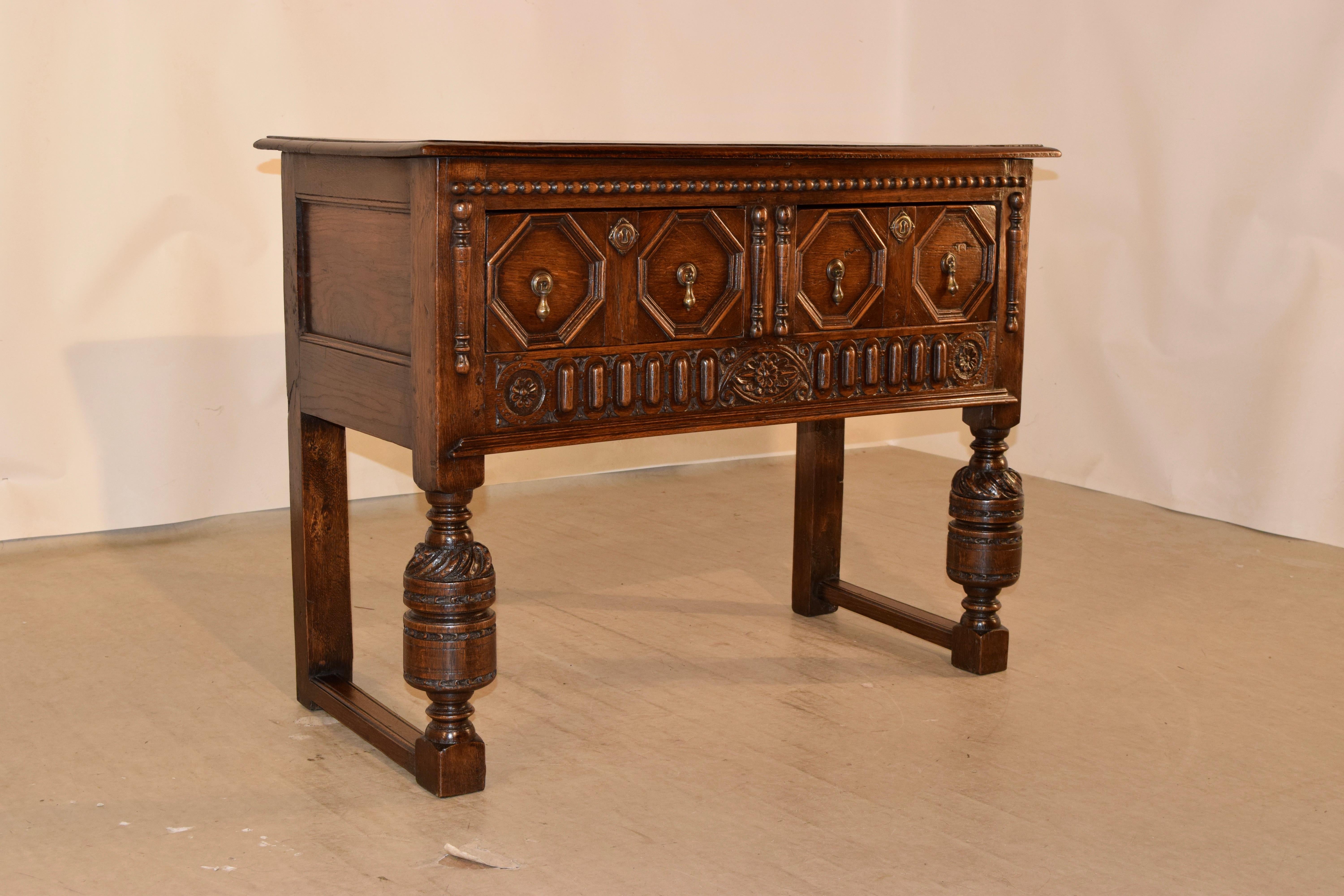 19th century oak sideboard from England with a beveled edge around the top, following down to paneled sides and two drawers in the front with raised geometric panels, flanked by hand-turned applied moldings and a beaded molding across the top. The