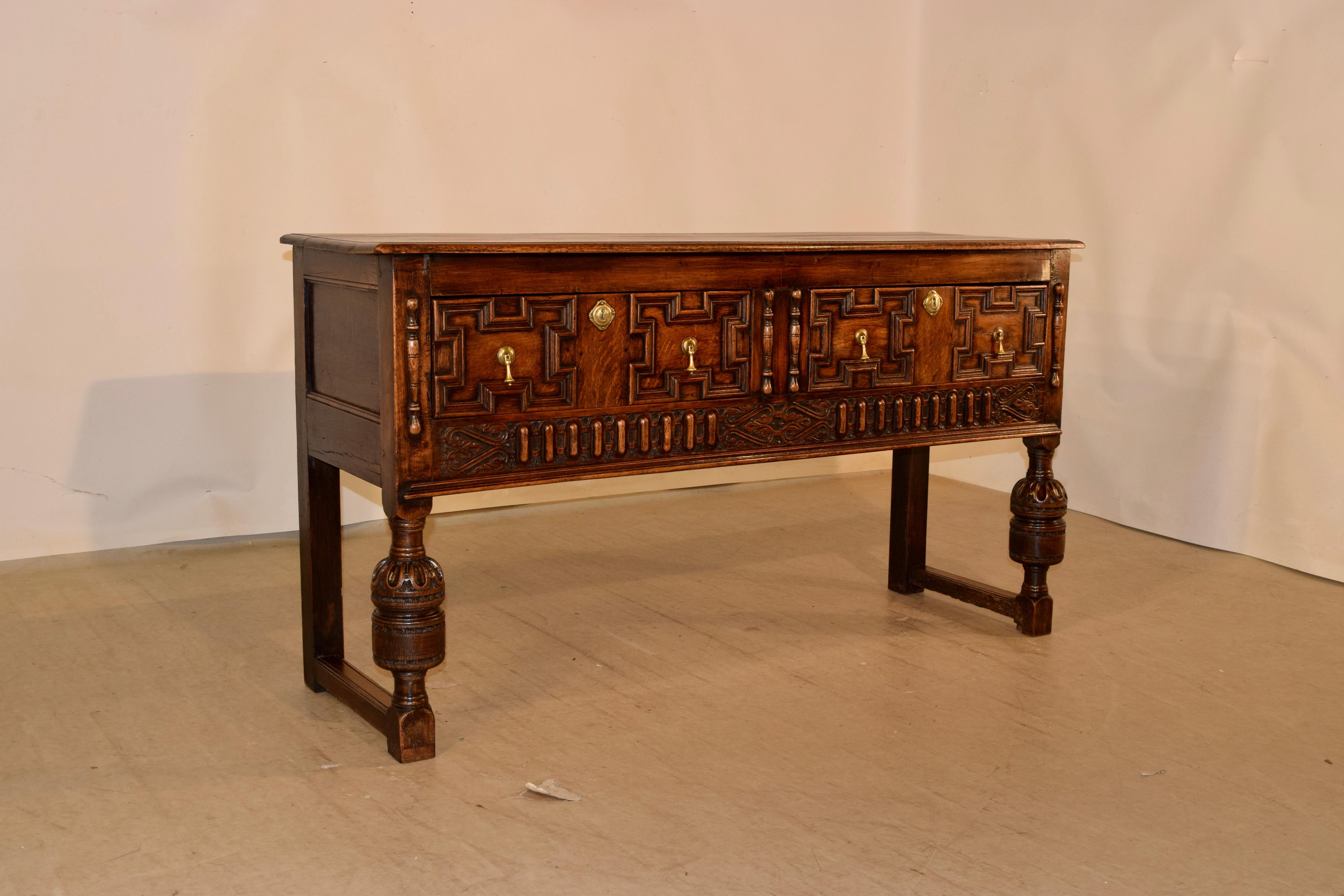 19th century oak sideboard from England with a beveled edge around the top, following down to paneled sides and two drawers in the front with raised geometric panels, flanked by hand-turned applied moldings. The apron is also wonderfully carved and