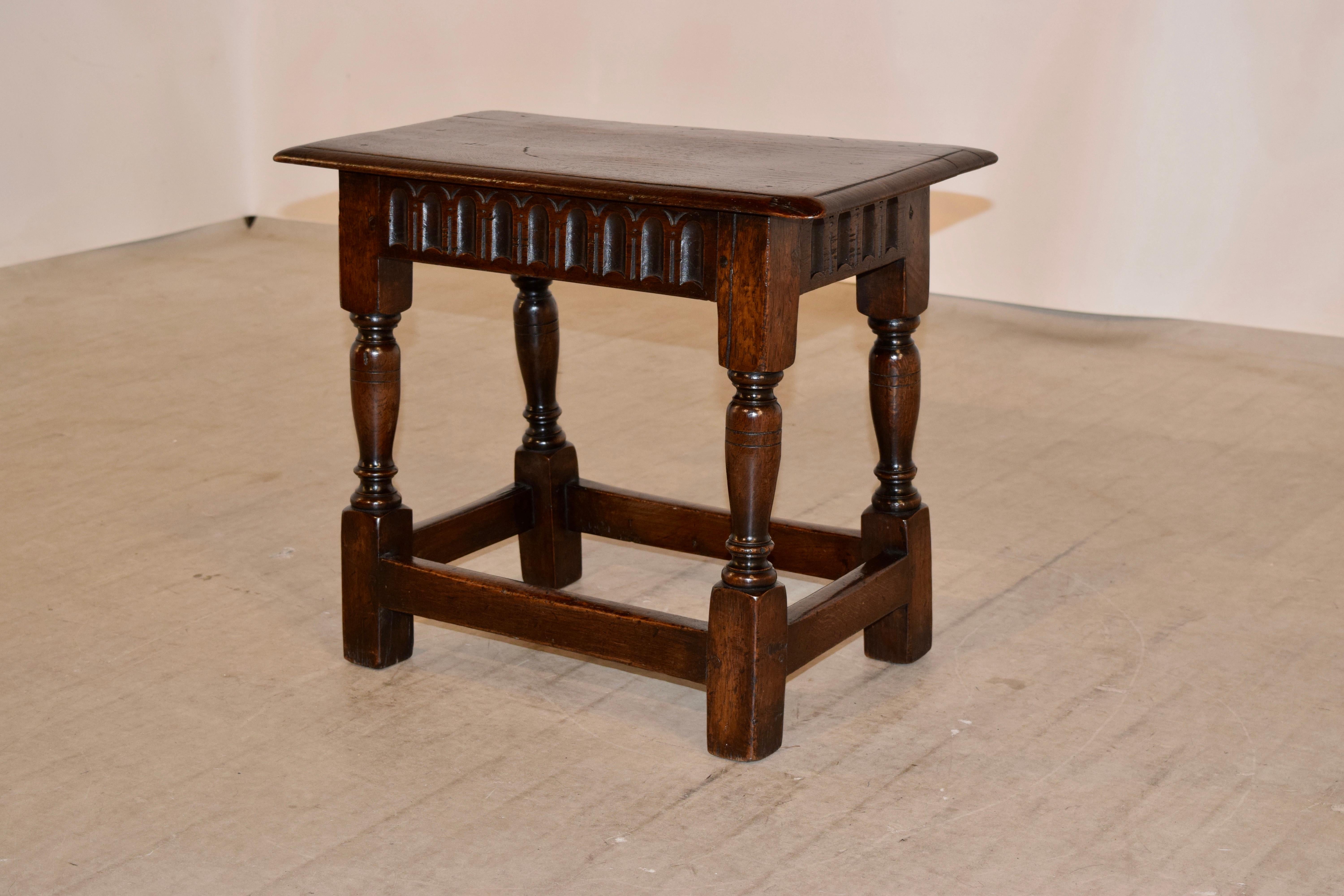 19th century English oak joint stool with a beveled edge around the top following down to a reeded apron and supported on hand-turned legs joined by simple stretchers.