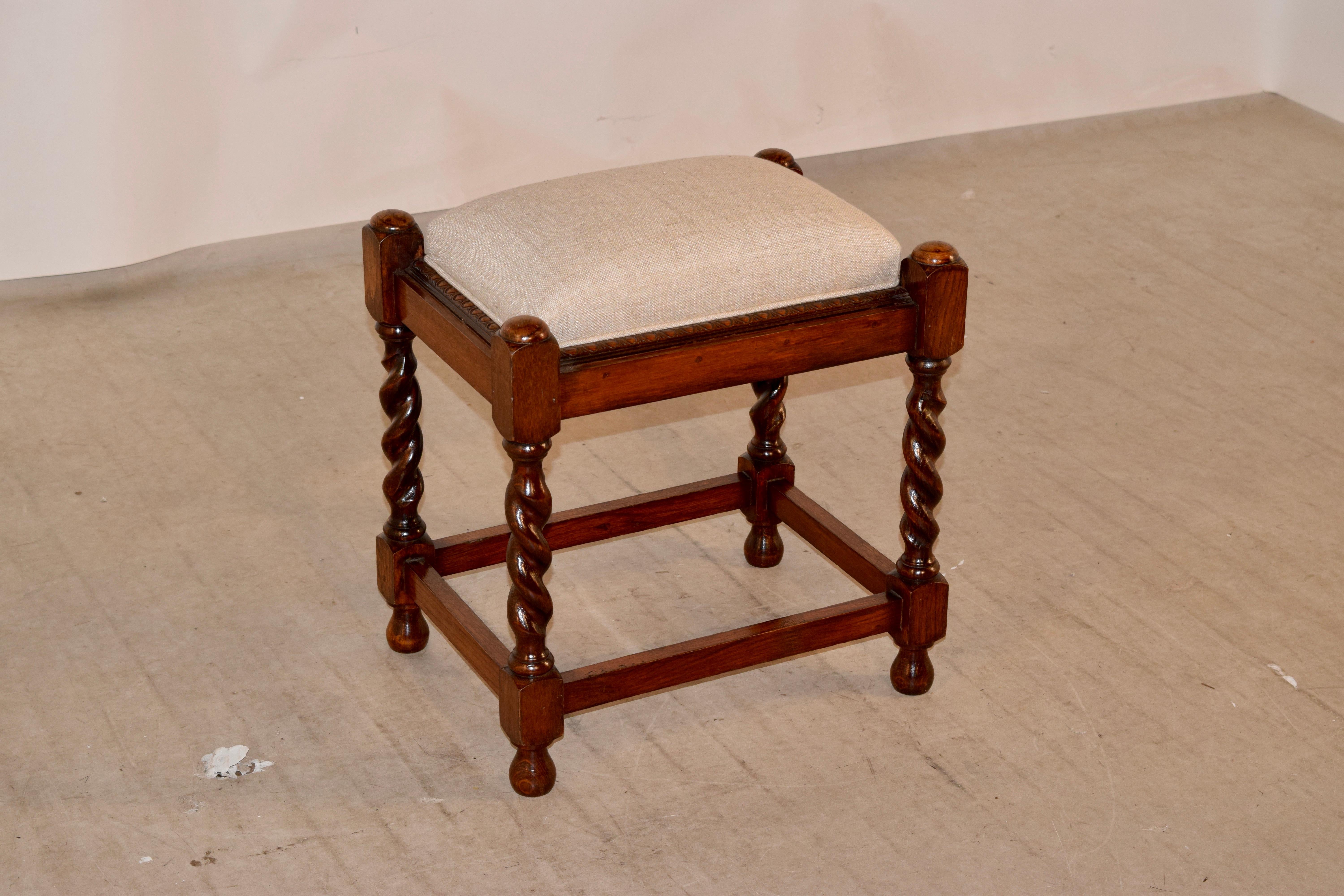 19th century oak stool from England wit newly upholstered linen seat. There are hand turned caps at the top following down to hand turned barley twist legs, joined by simple stretchers and supported on hand turned feet. Lovely form.