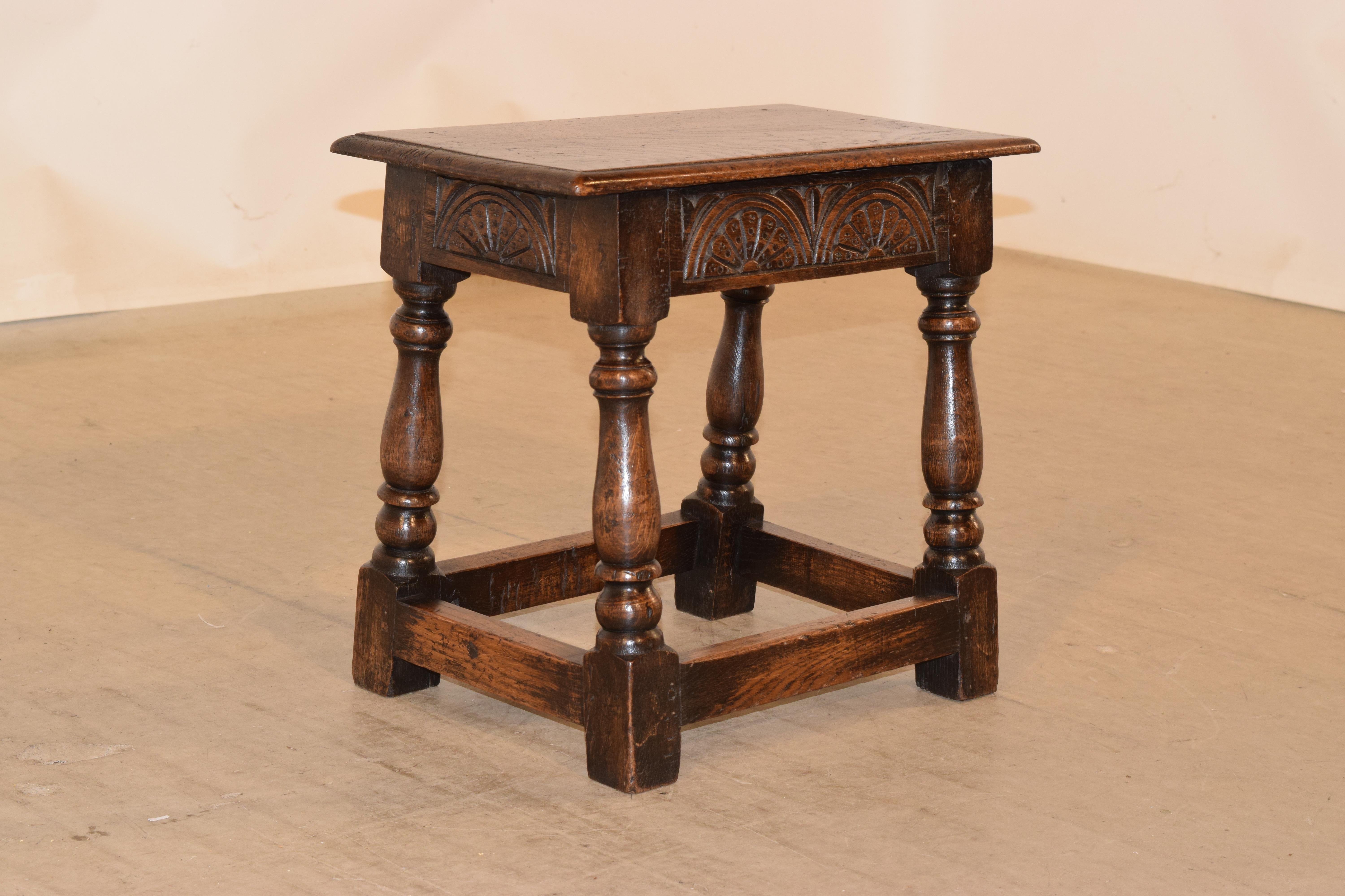19th century oak joint stool from England with a beveled edge around the top, over a simple apron with hand carved lunette decoration and supported on hand turned and splayed legs, joined by simple stretchers.