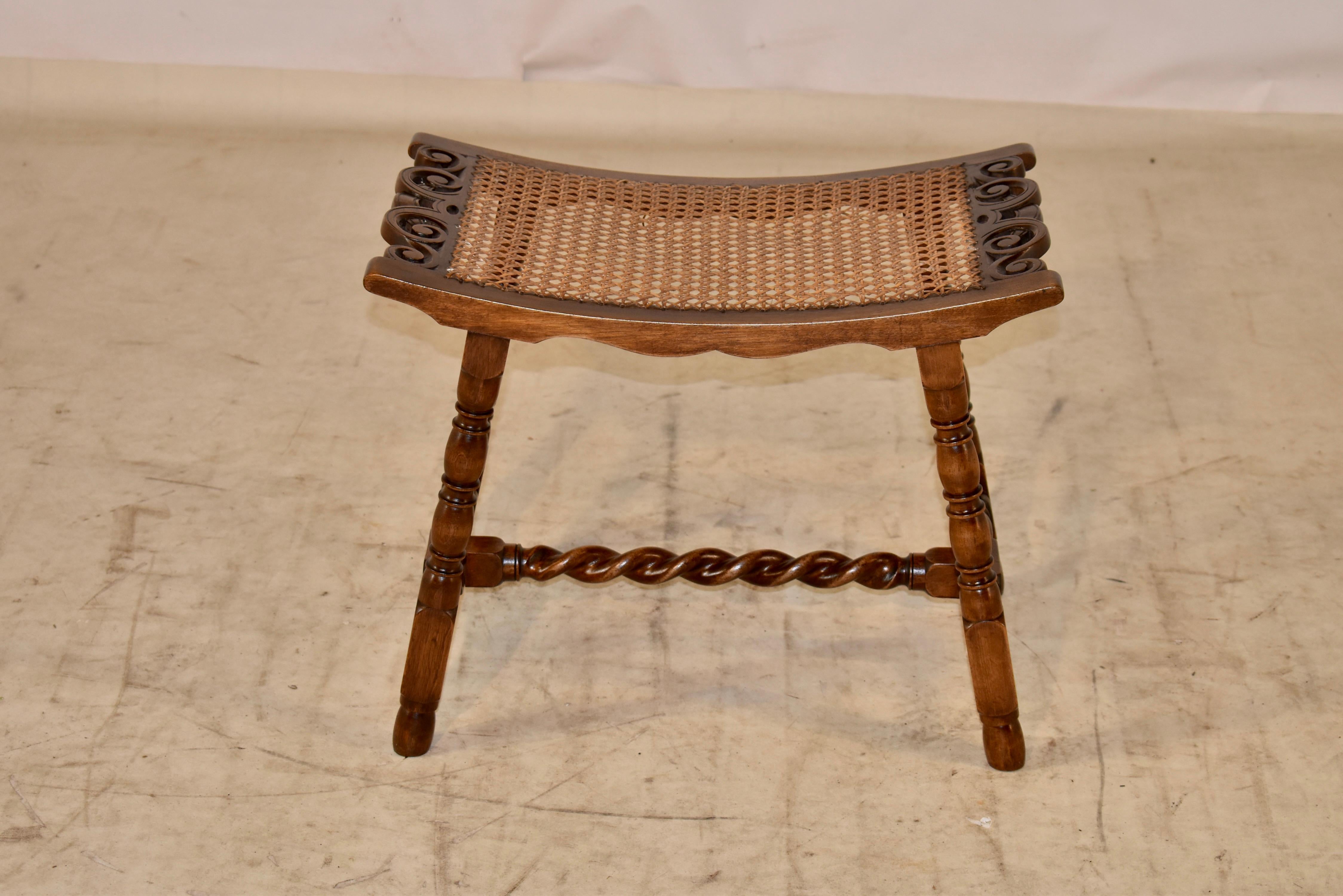 19th century oak stool from England with a played top which has hand carved sides and pierced decoration for added design interest. The seat retains its original caning. The seat is supported on hand turned and splayed legs, joined by turned