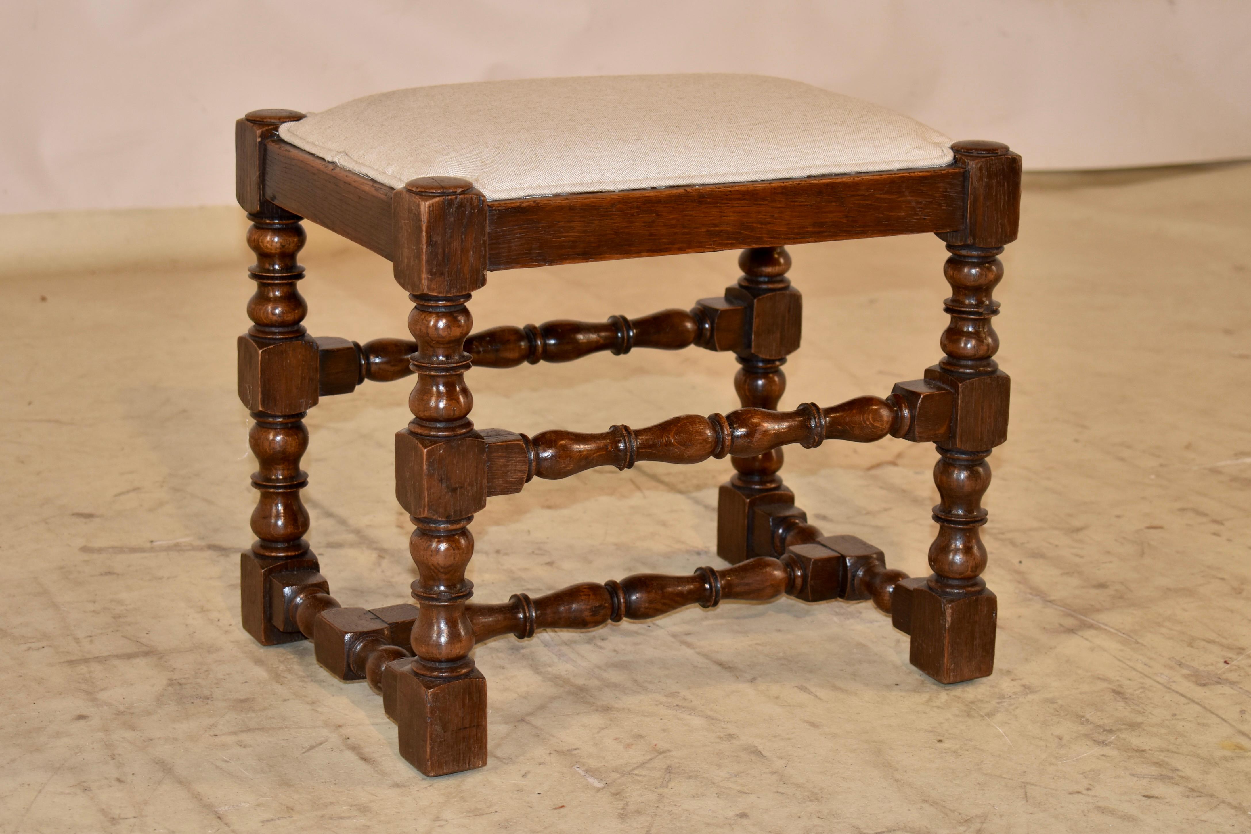 19th century oak turned stool from England.  The seat has been newly upholstered in linen, finished with a single welt, for an updated look.  The frame of the stool is hand turned with a simple apron and lovely bob and stop turned legs, joined by