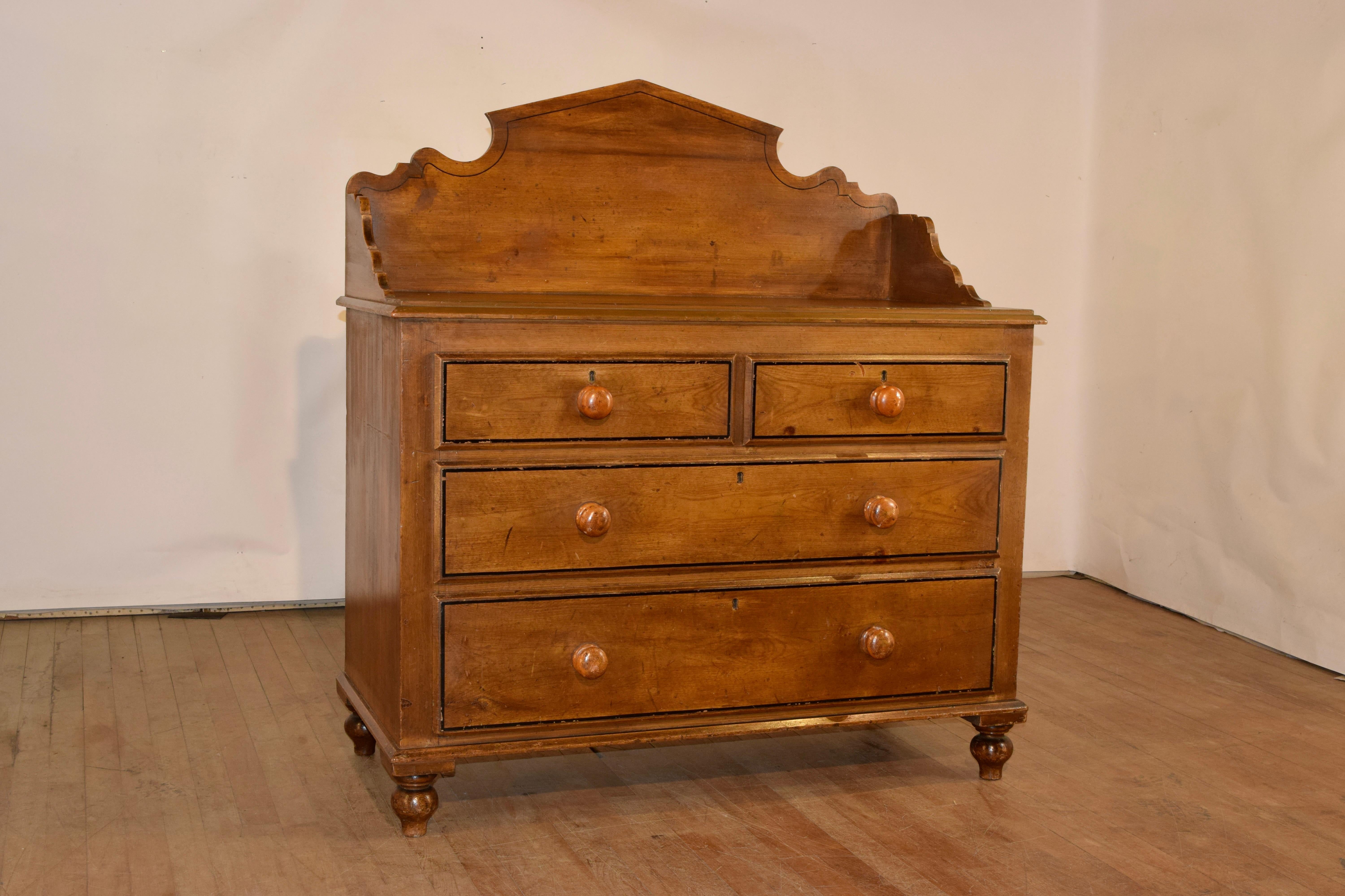 19th century oak washstand from England with a wonderful hand scalloped backsplash. The top of the chest measures 32 inches in height, and has a beveled edge, following down to two over two drawers, all with painted banding around the drawers for