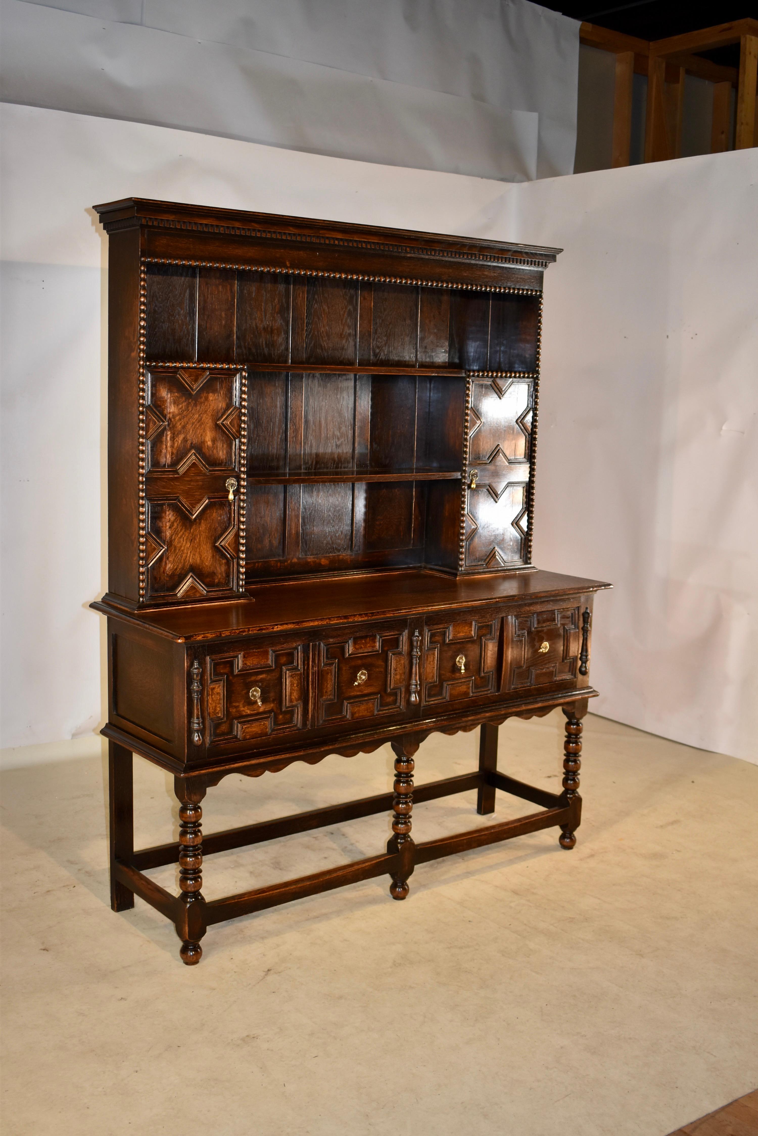 19th century oak Welsh cupboard from England. The cupboard is made in two pieces for easy moving. The top has a crown over a simple apron with beaded trim and solid plank back boards. There are two shelves, flanked by two cupboard doors, both with
