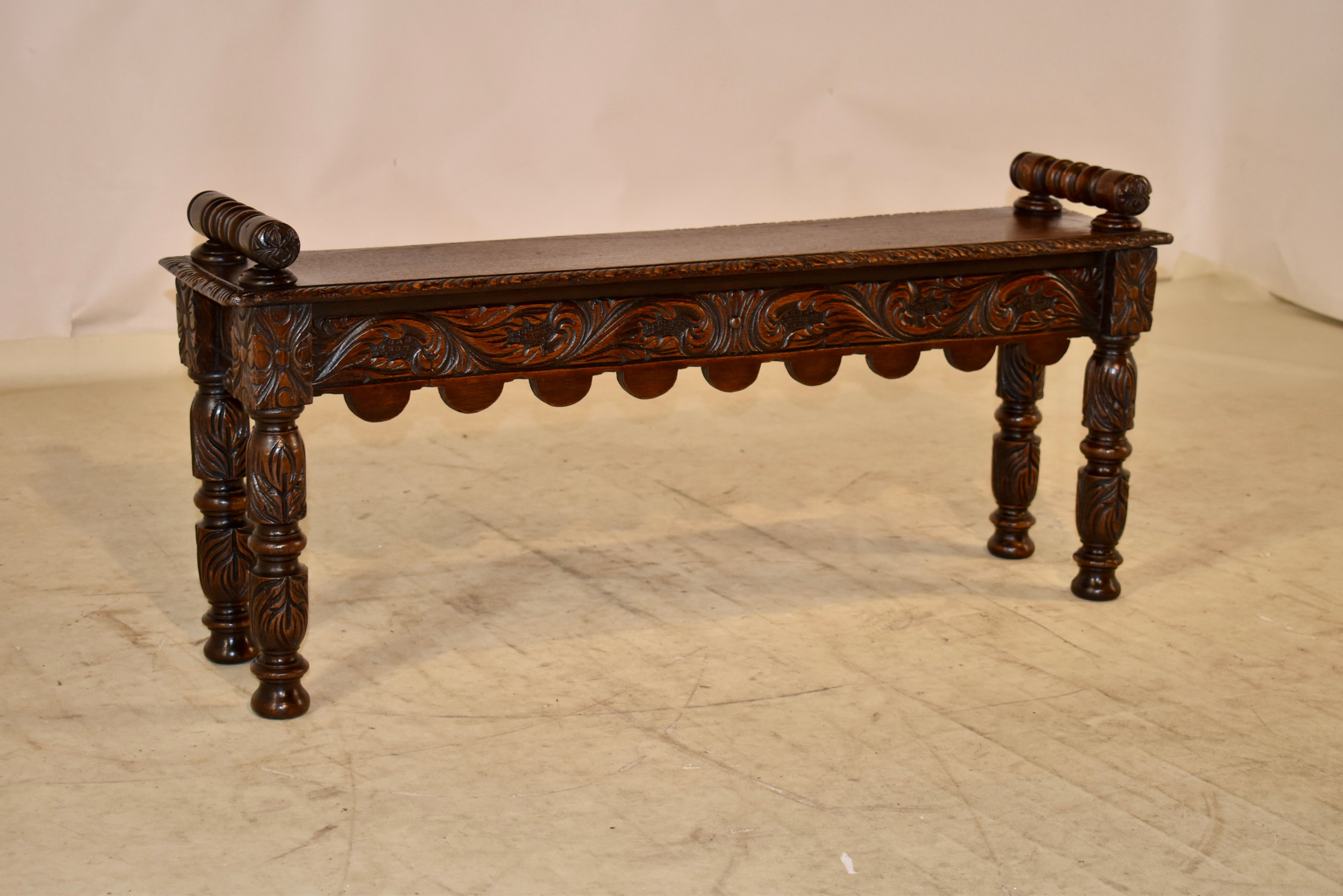 19th Century oak window seat from England. This piece has lovely hand carved decorated arms attached to the seat, which is made from a single board. The seat has a beveled and hand carved decorated edge, and follows down to a lovely apron, which is