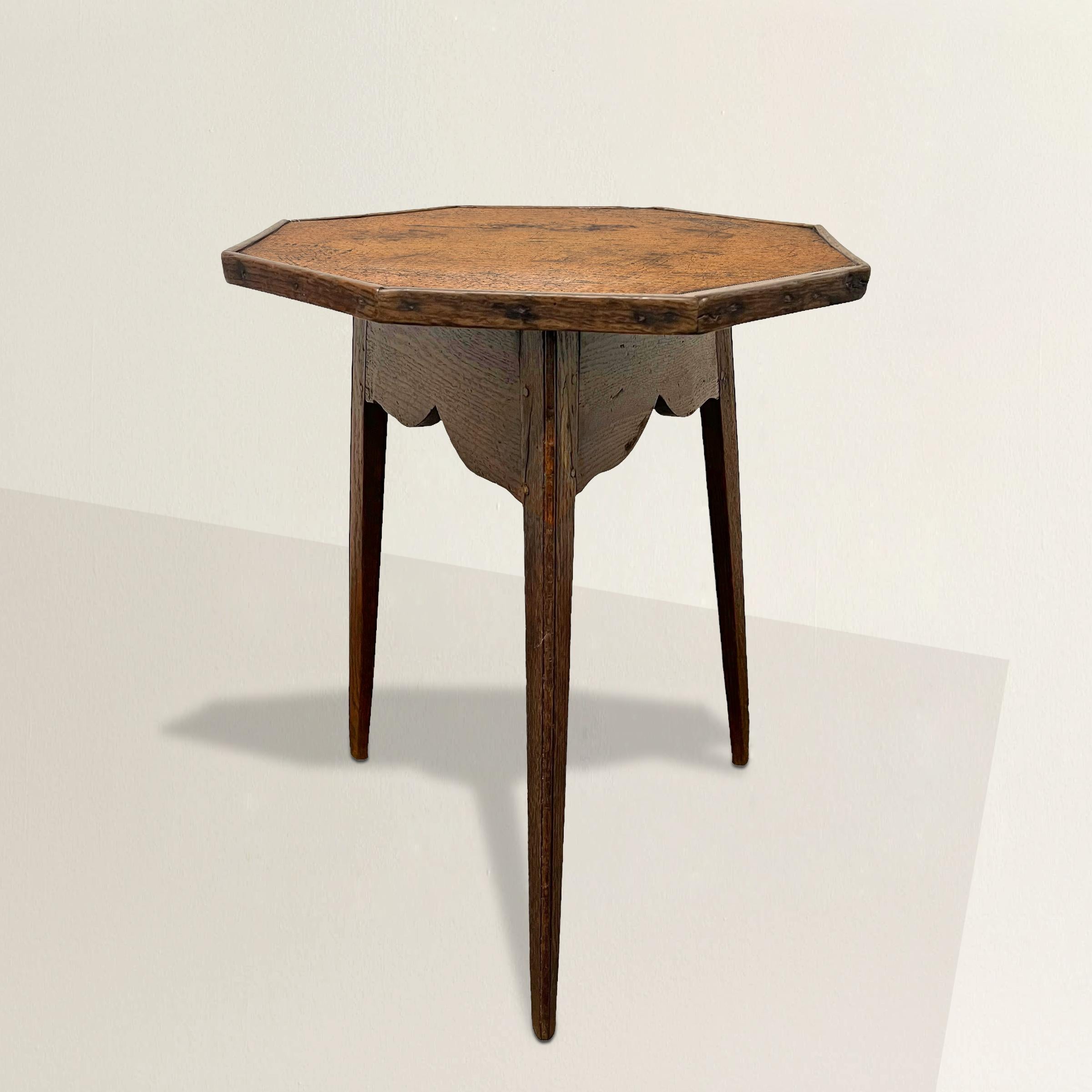 Step back in time with this early 19th-century English cricket table, a true gem of craftsmanship and history. Its striking octagonal top, fashioned from a single solid plank of elm, showcases the exquisite beauty of natural woodgrain. Supported by