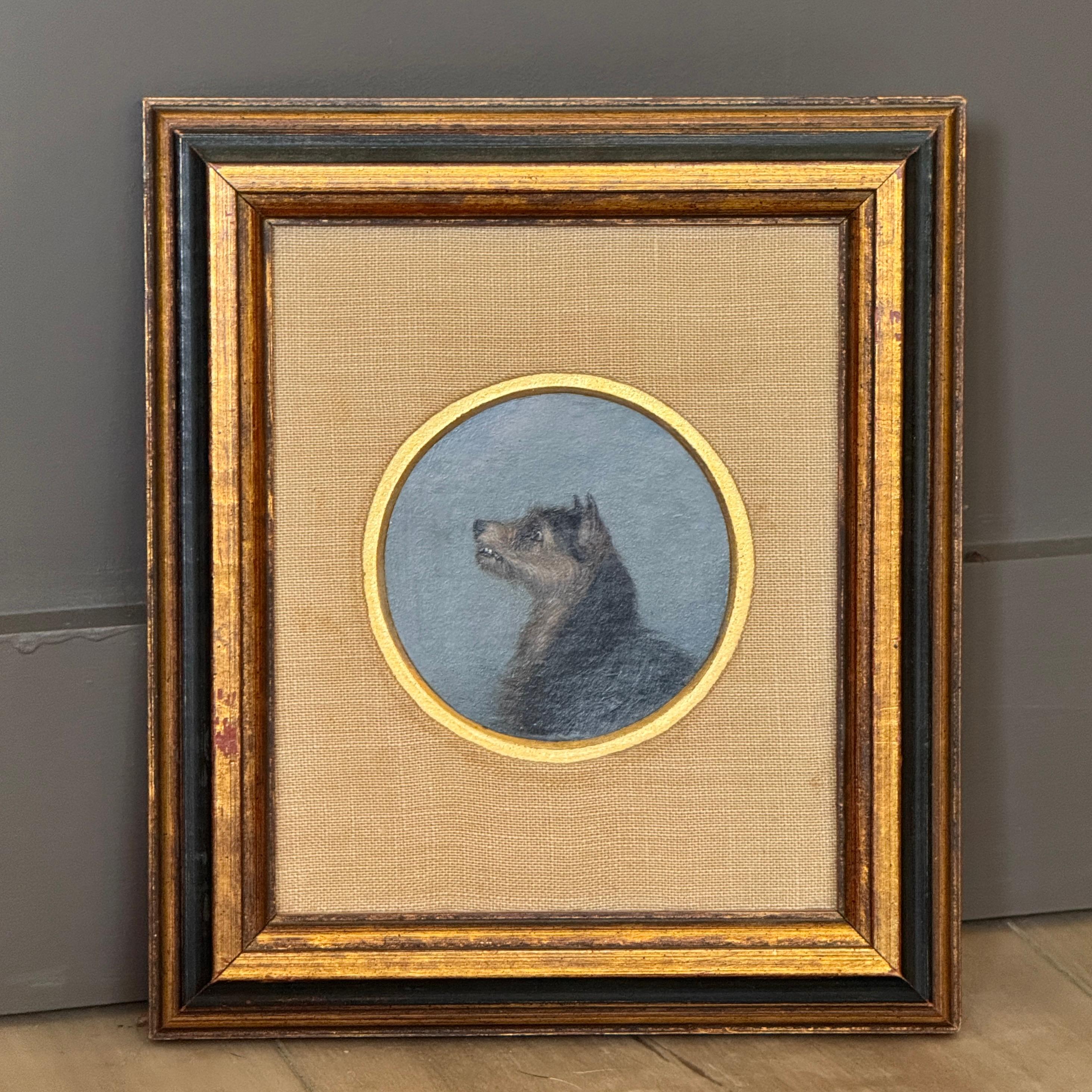 Charming 19th C. English oil-on-board profile portrait of a terrier. The small round composition is set against a blue-gray ground, framed within a linen mat and gilt-trimmed wood frame.
