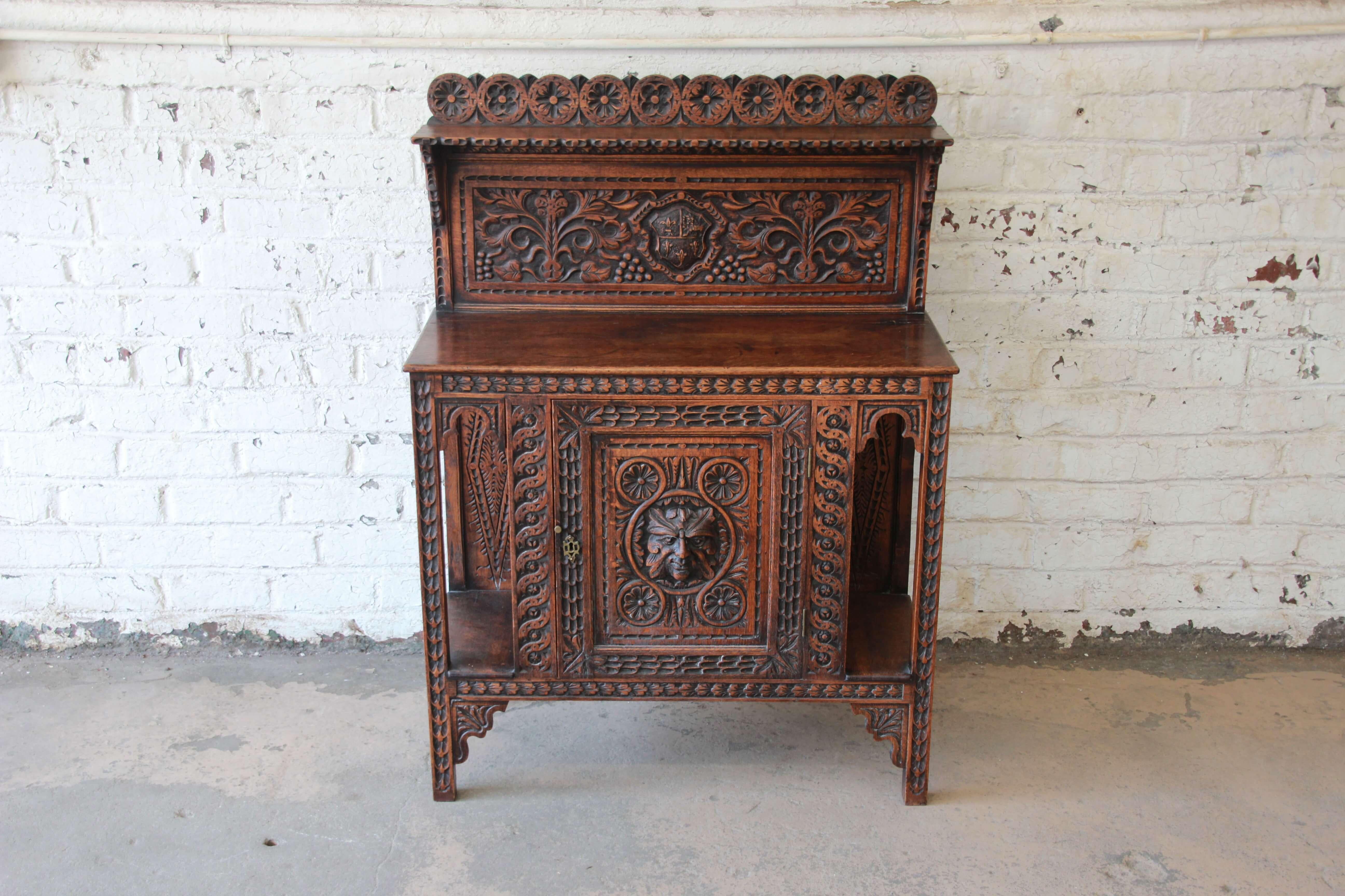 Offering a rare and stunning 19th century ornately carved sideboard or bar cabinet. This piece features carved details throughout the entire piece with fantastic carved face in the centre of the cabinet door. The door opens up to a shelf offering