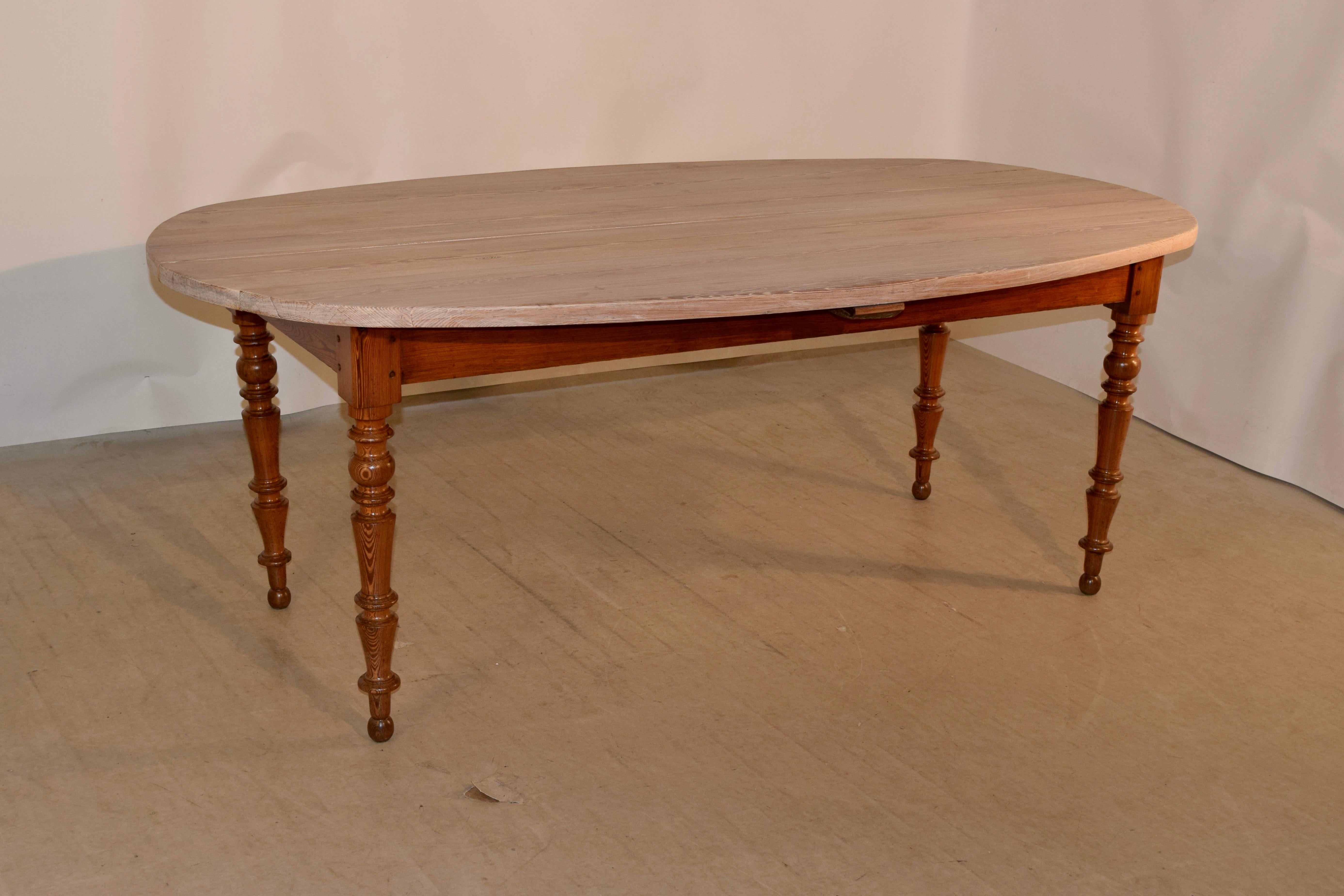 Unusual 19th century English pine farm table with oval shaped scrubbed pine top. The top is made from thick pine planks and follow down to a simple apron, which measures 23.63 inches in height. The table is supported on hand turned legs. Lovely form.