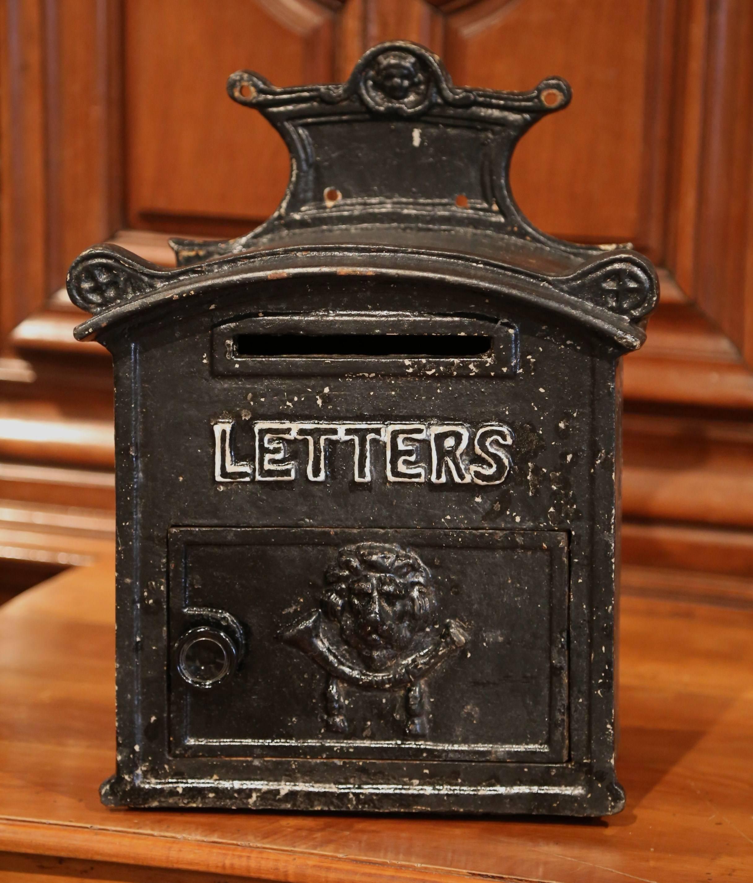 This elegant, heavy iron mailbox was forged in England, circa 1880. The impressive, wall hanging mail holder features a classic lion head with a letter slot on the front door. This exterior piece is in excellent condition and has its original