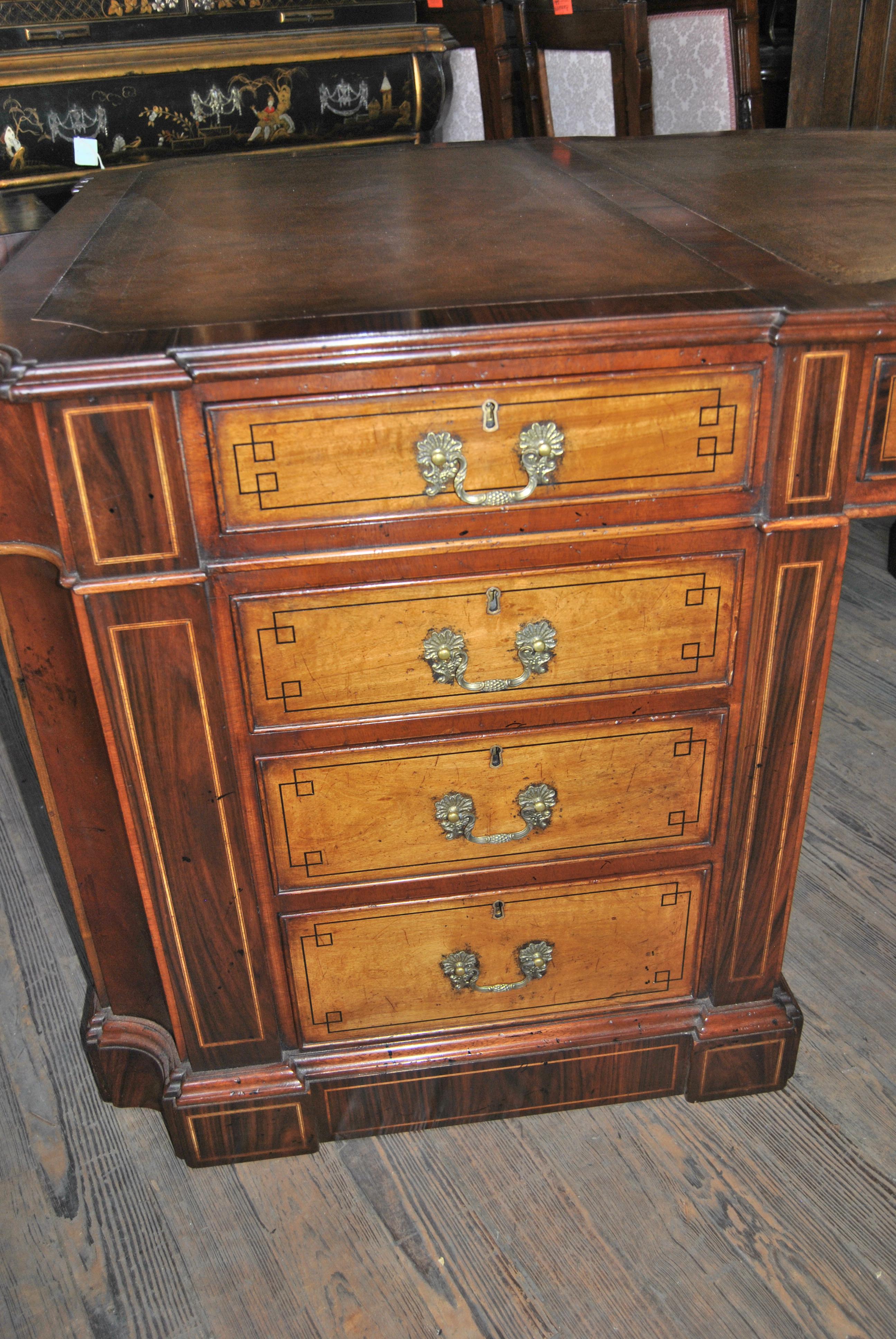 This is a partners desk made in England, circa 1890. The desk is made of a combination of rosewood, mahogany, satin mahogany and ebony. The top of the desk is made of rosewood and has three beautifully shaped pieces of brown leather with gold