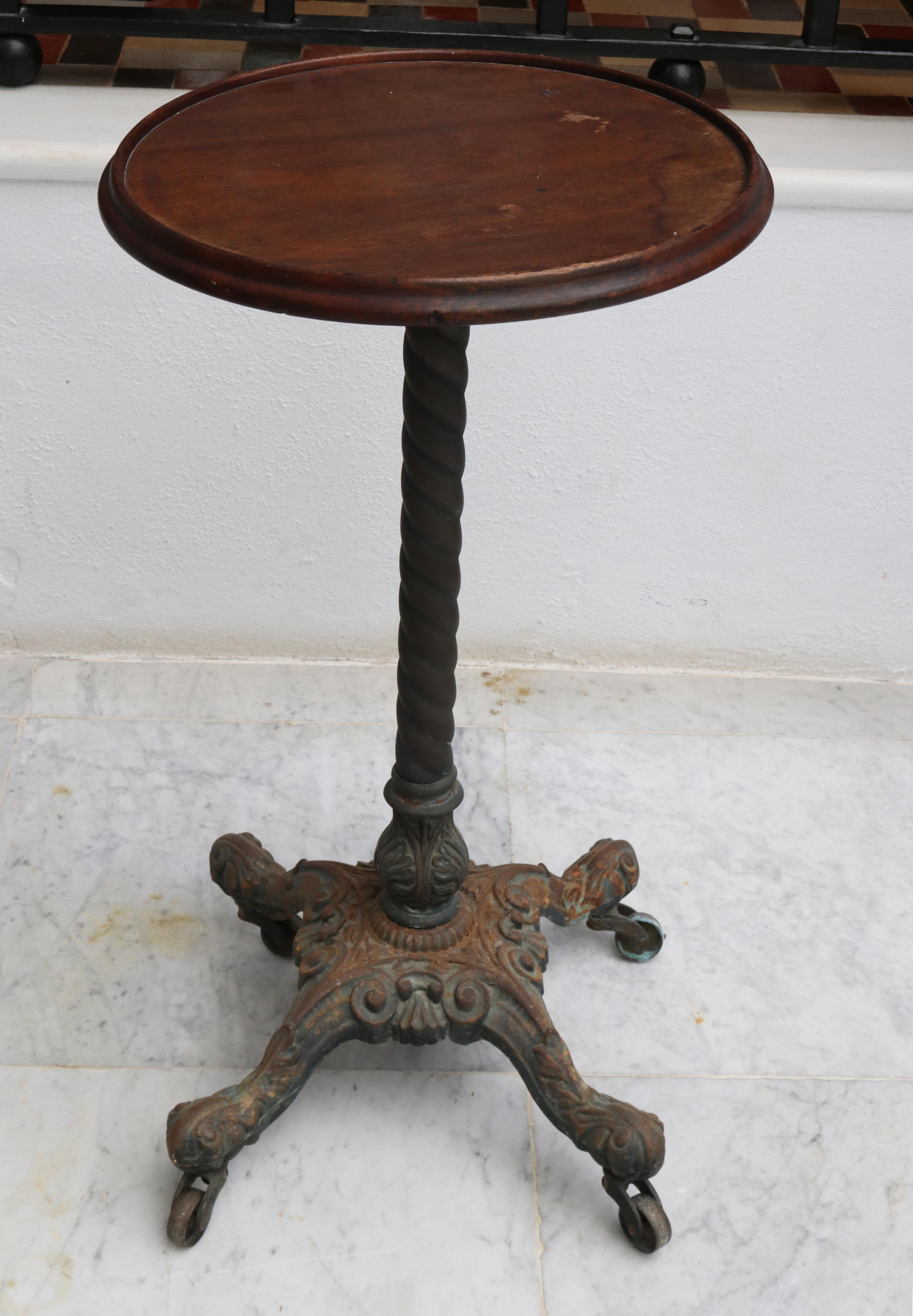 19th century English pedestal side table with wooden top and cast iron foot claw with four wheels.