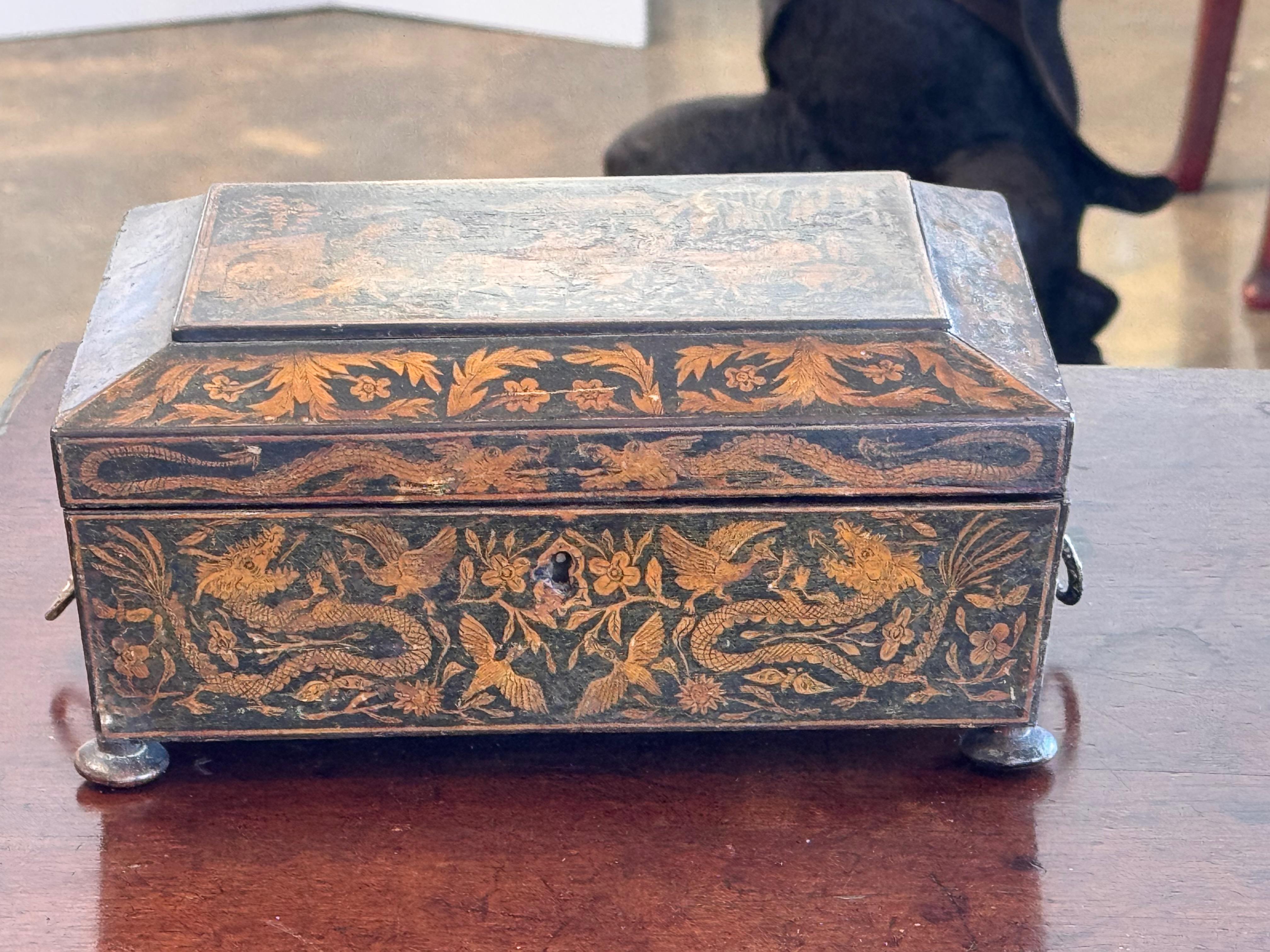 This exquisite English penwork box is a fine example of intricate craftsmanship, featuring a beautifully hand-decorated surface with elaborate chinoiserie-style motifs. Delicate gold detailing depicts scenes of figures, horses, and floral elements,