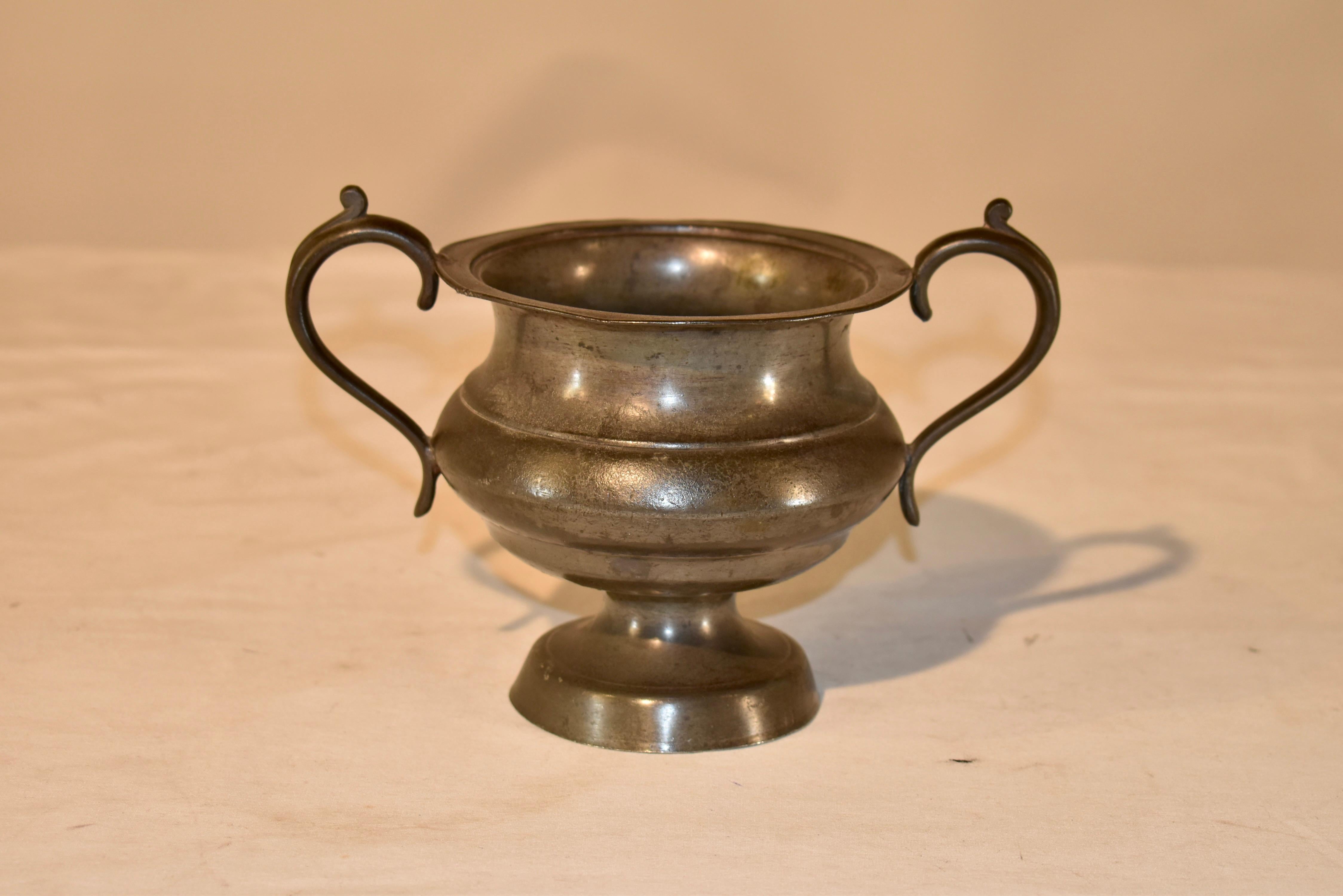 Early 19th century pewter urn from England.

The form is la wonderfully bulbous shape with a handle on wither side which feature spurs and a lovely serpentined shape.  The base is simple and has a nice height.  

This would look gorgeous with
