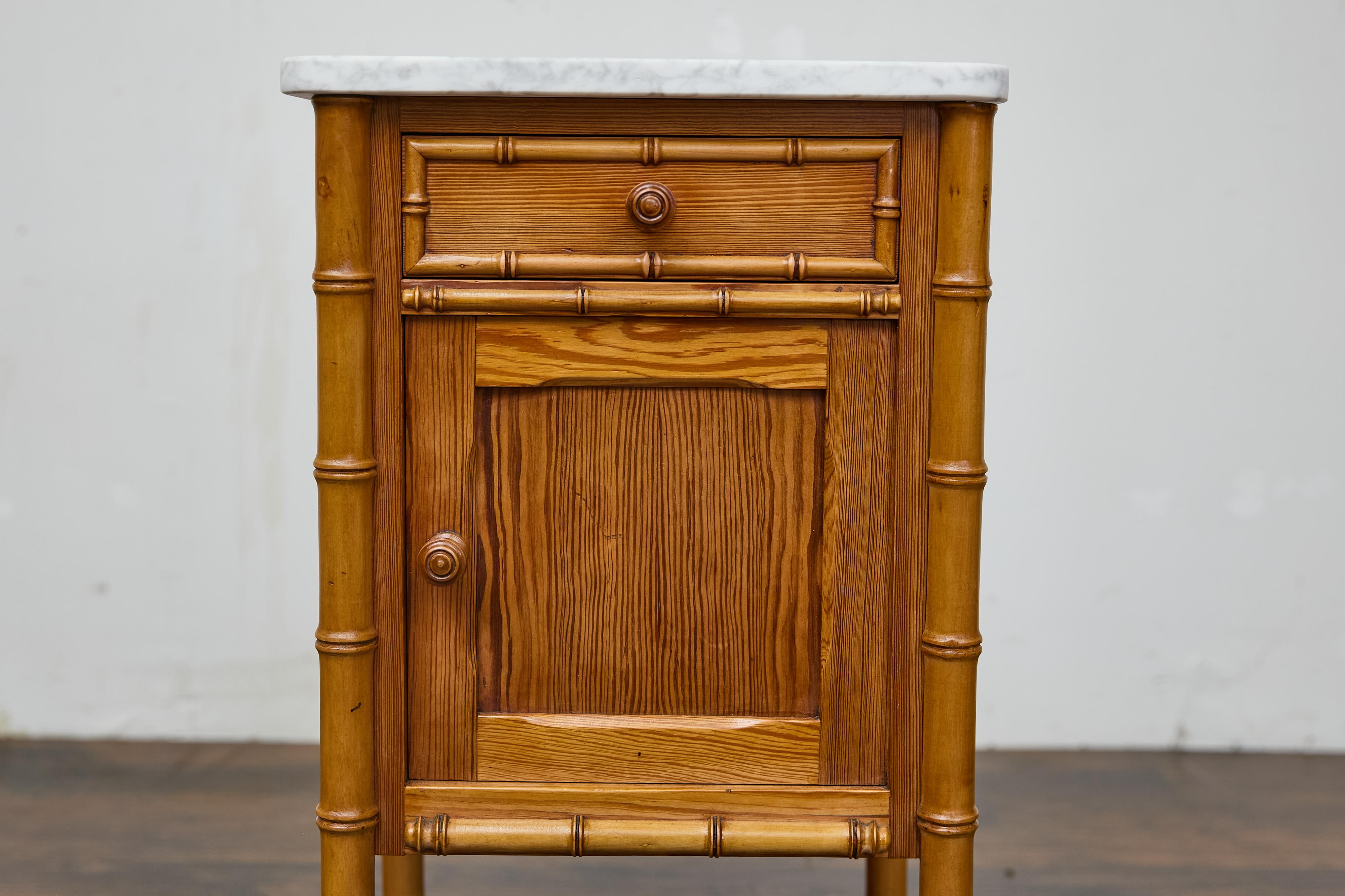 Comodino inglese in pino finto bambù del XIX secolo con piano in marmo bianco. Realizzato nell'Inghilterra del XIX secolo, questo comodino in pino emana un fascino senza tempo grazie ai dettagli in finto bambù e alla patina calda. Le venature