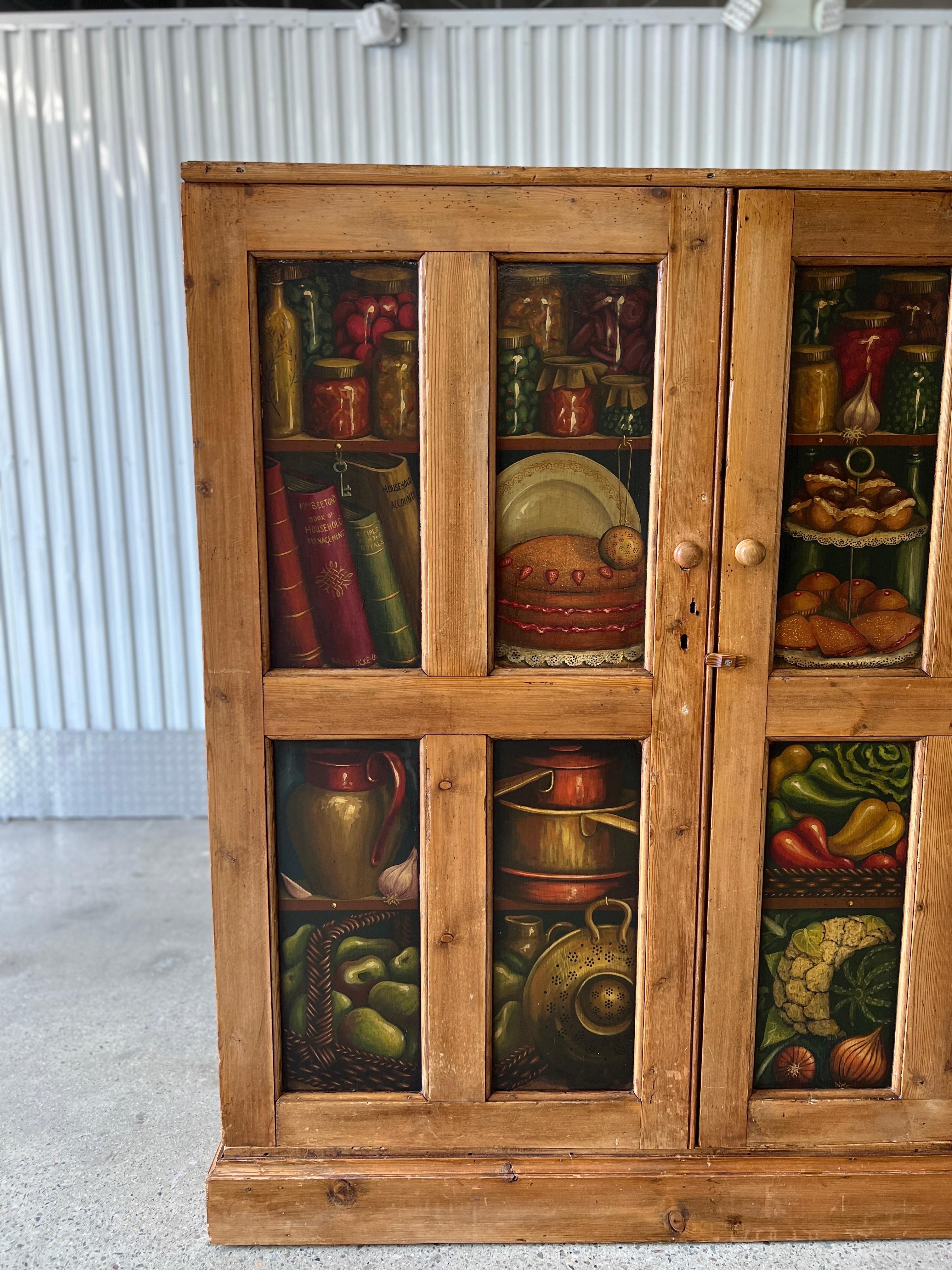 English, 19th century.

A beautiful antique English pine cupboard cabinet which has 8 individually painted panels to the exterior showcasing fruit, vegetables, books, wine bottles, books and cooking pots. The Trompe L'oeil paintings are done very