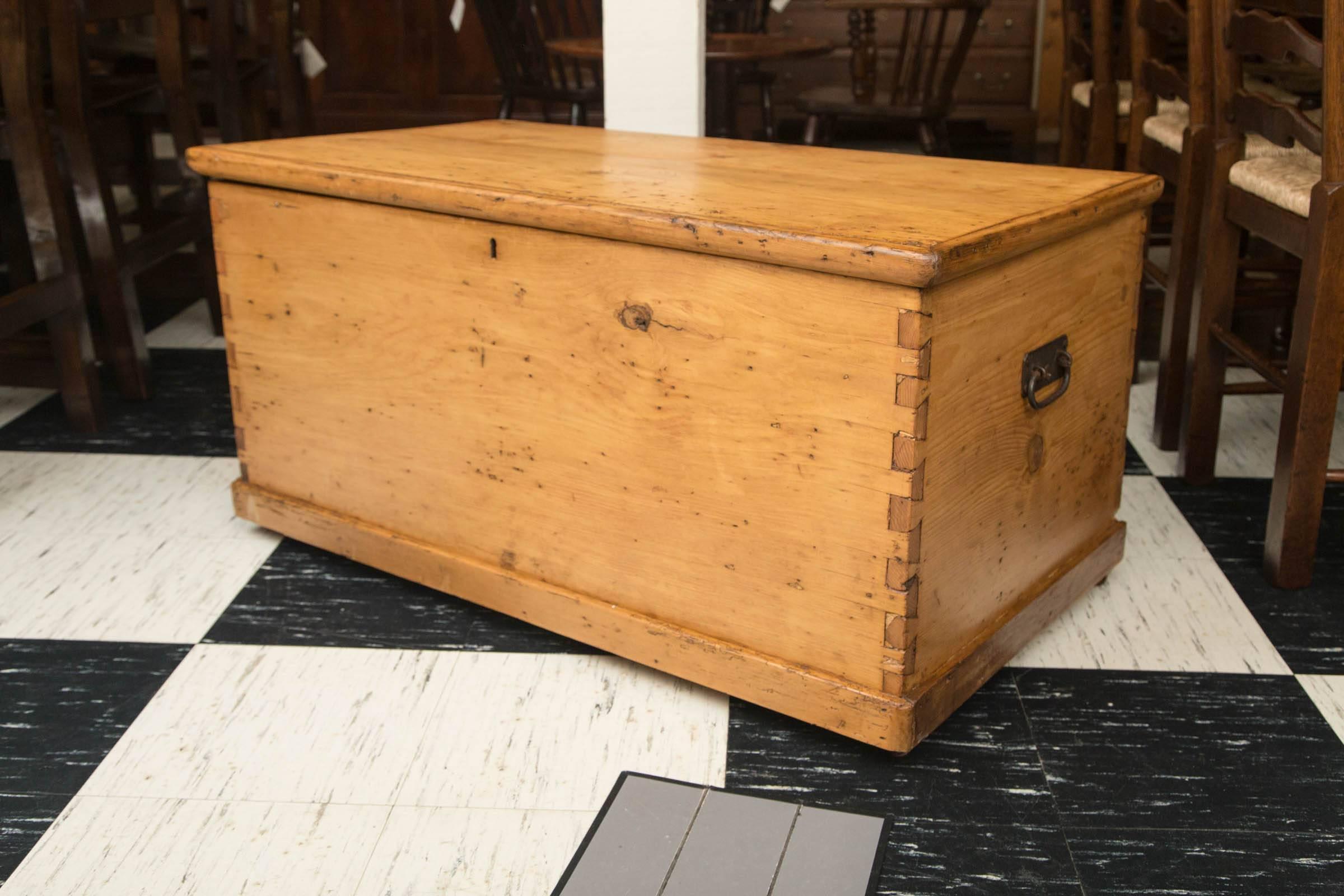 19th century English pine chest with candle drawer with wrought iron handles. Dovetail construction. Chest rests on original casters.