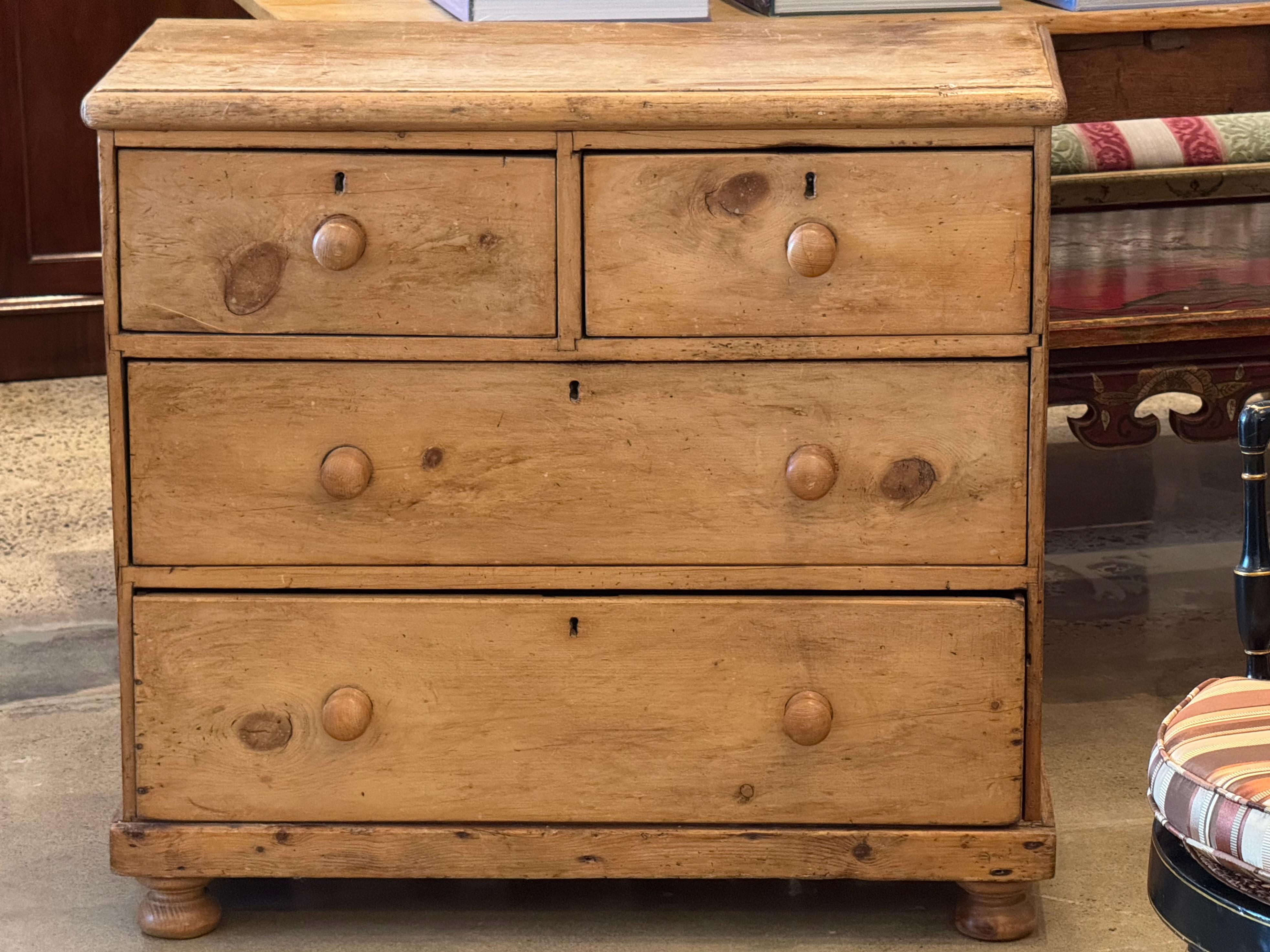 Rustic English pine chest with a warm, natural patina. The simple, functional design features two smaller drawers over two larger ones, all fitted with wooden knobs. Traditional joinery and solid construction highlight its 19th-century
