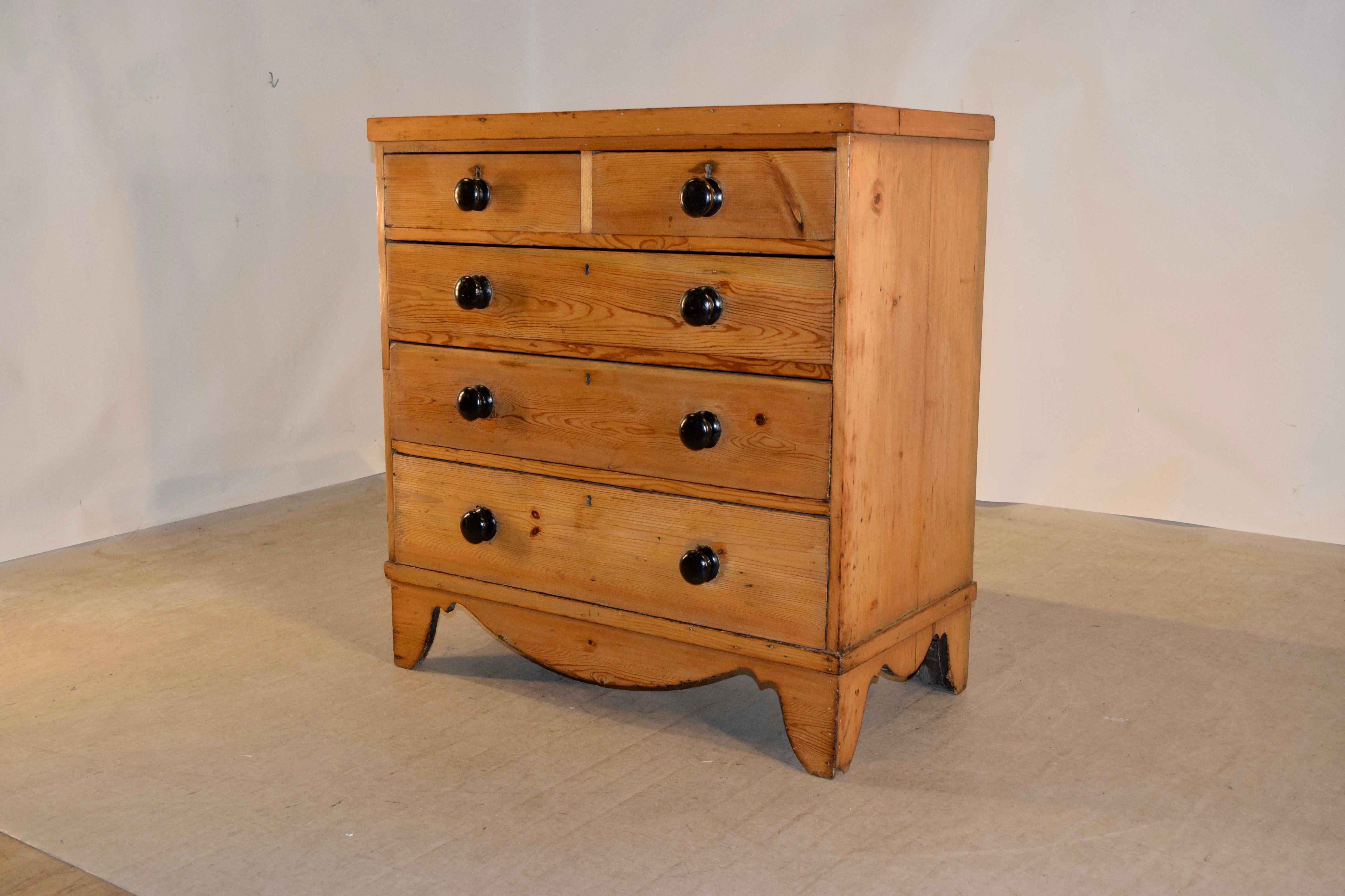 19th century pine chest from England. The top has a banded edge and follows down to simple sides and two over three drawers in the front. The case is elegant and simple and has old repairs. Raised on hand scalloped bracket feet.