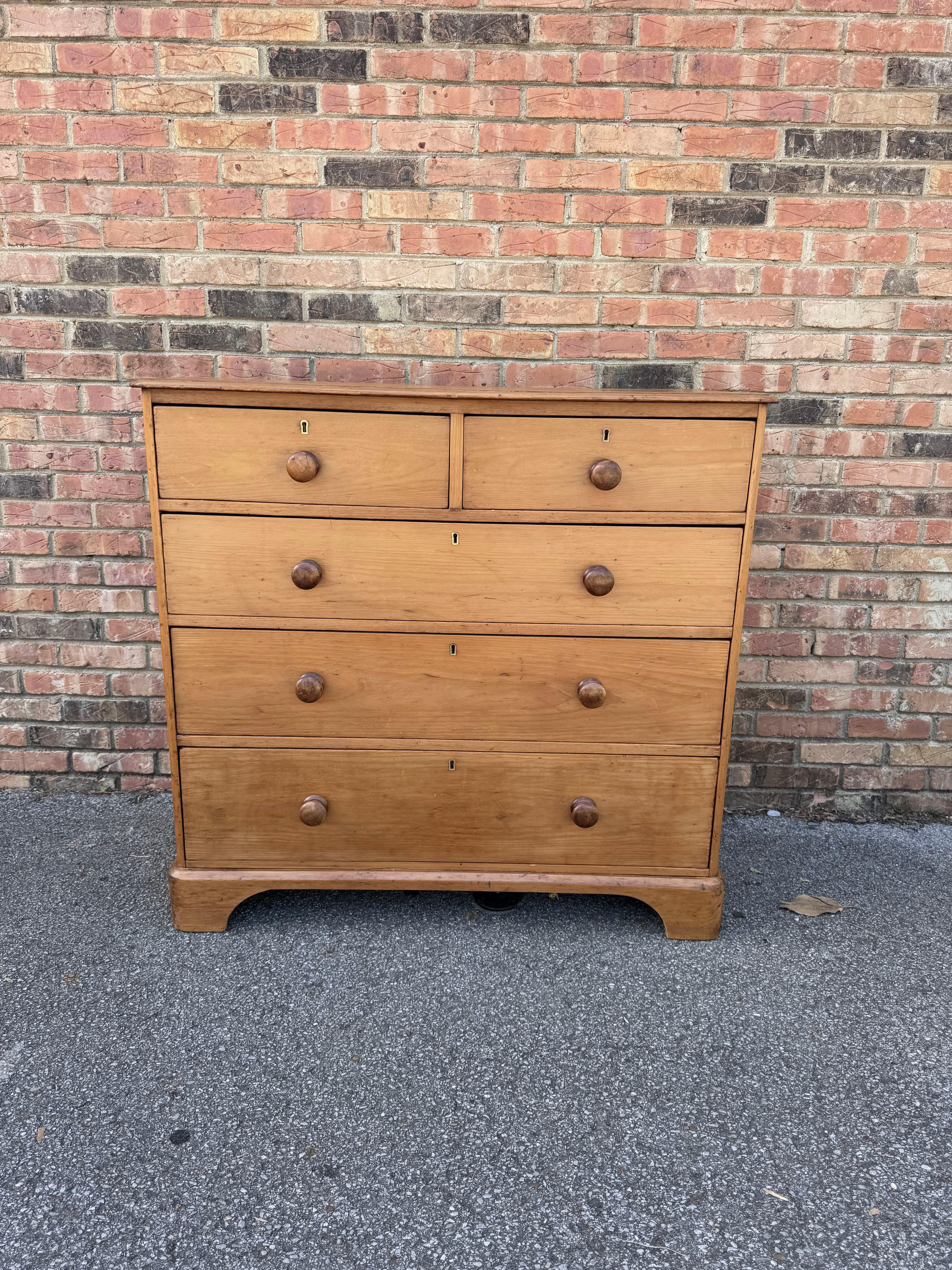 This piece dates to the 19th century and has lovely patina. The wood has a warm glow, that is accented perfectly by the darker stained knobs. Being a two over three design with a casual simple feel. This chest would make an excellent addition to a
