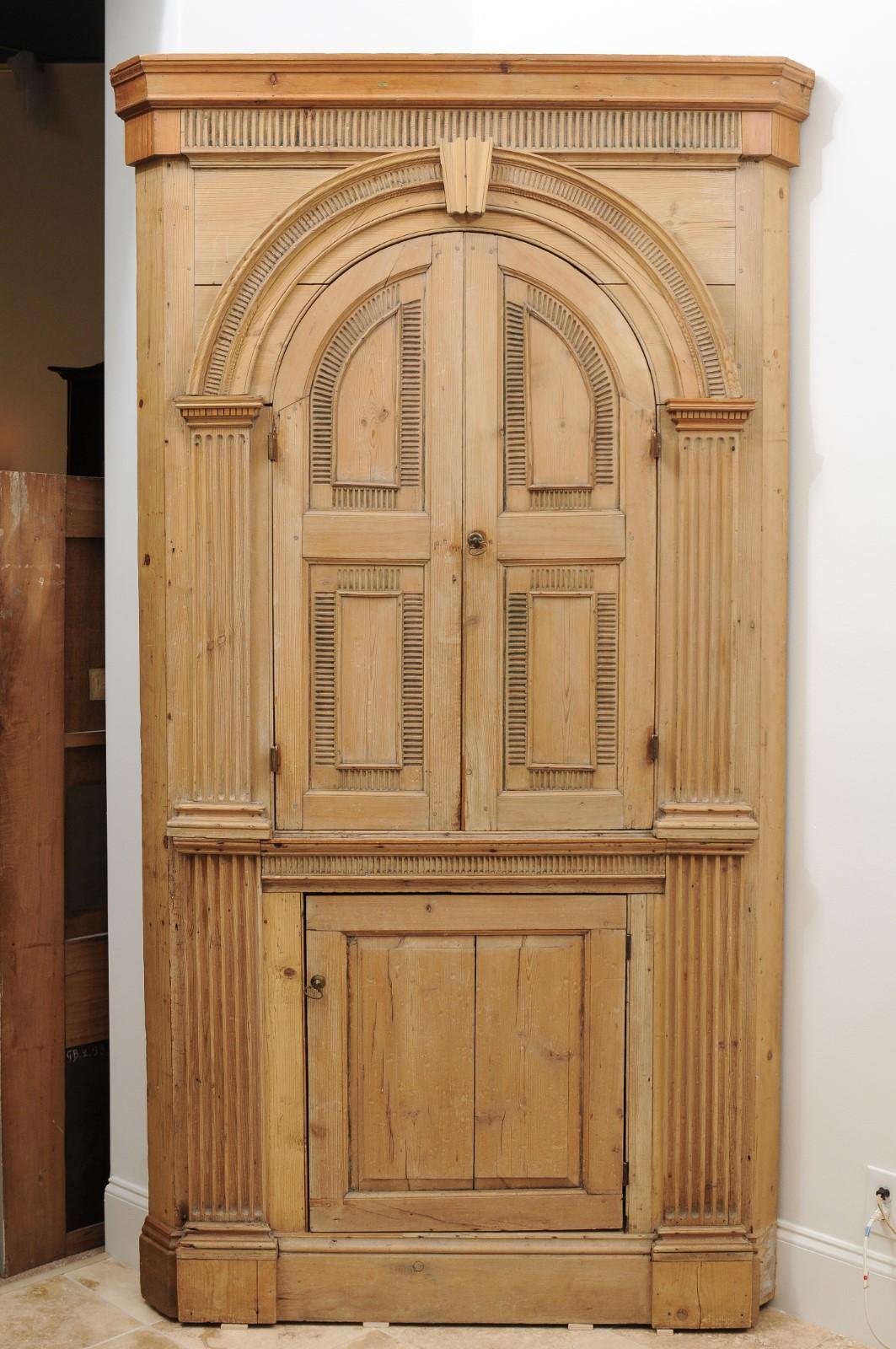 19th Century English Pine corner cupboard with arched upper cabinet above lower cabinet door.