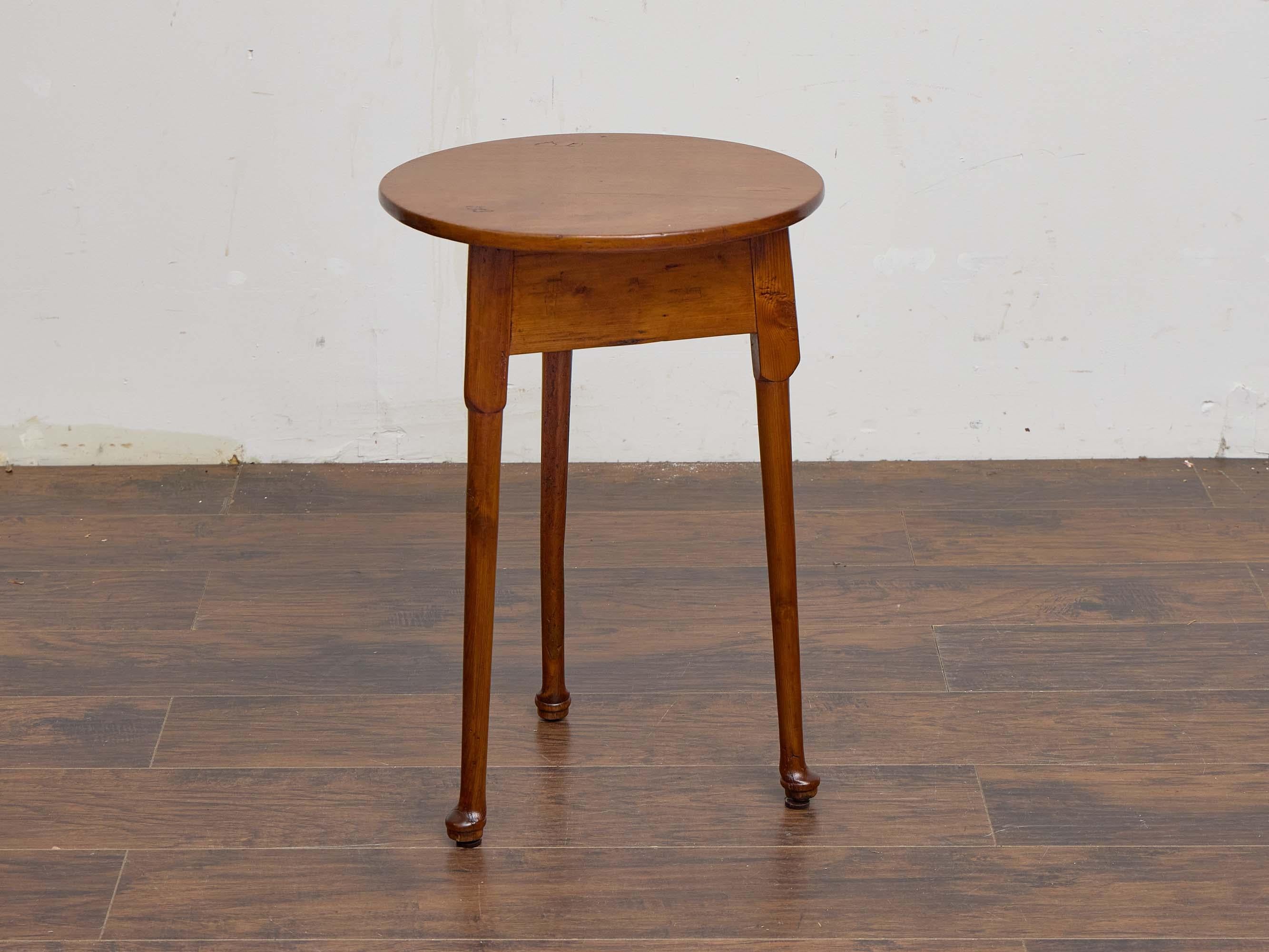 A charming 19th-century English pine cricket table, notable for its honest craftsmanship and warm patina. The circular top rests on three tapered legs that end in small pad feet — a subtle yet refined detail typical of rural joinery from the period.