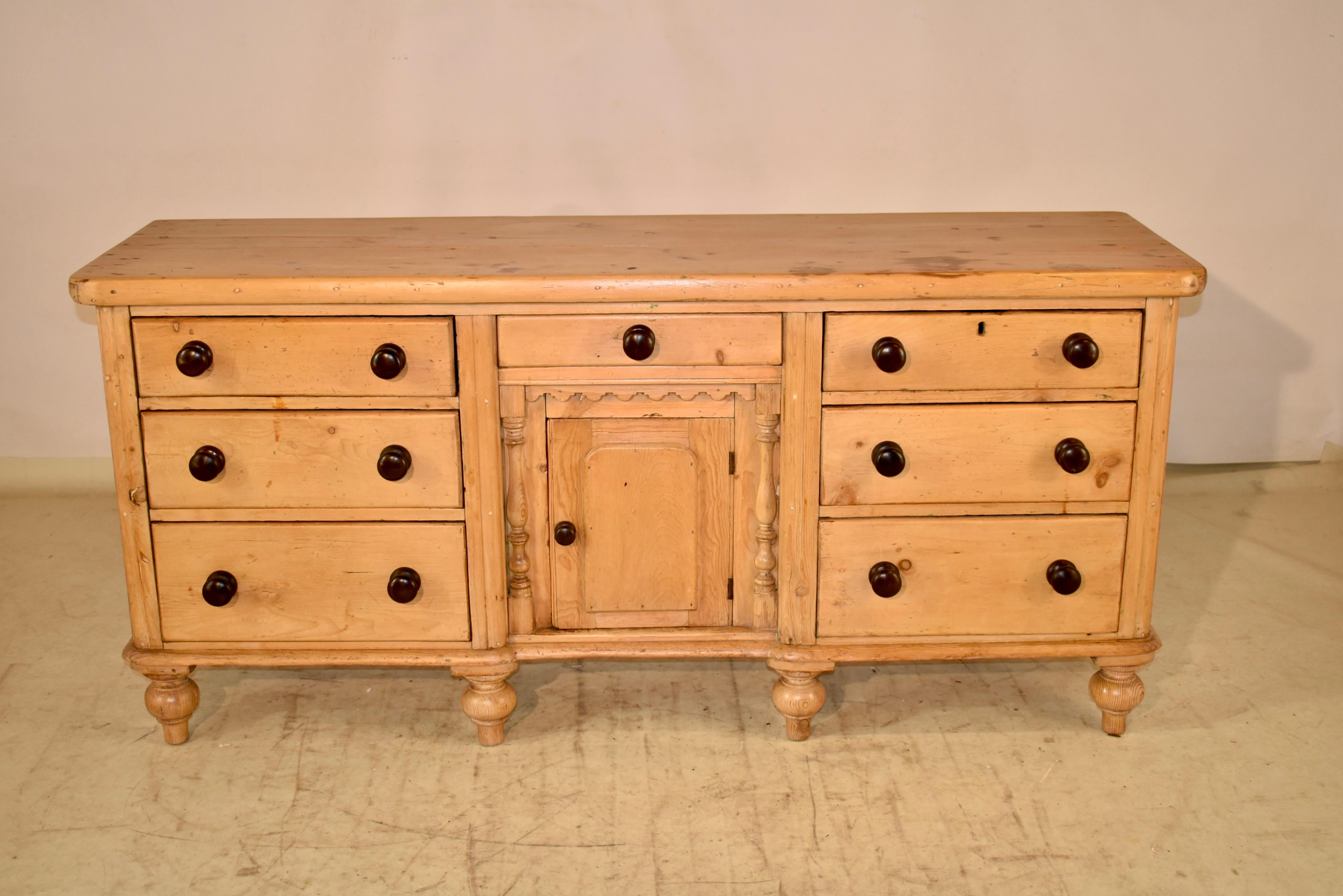 19th century pine dresser base from England.  This fabulous piece has a thick two plank top, which follows down to a central single drawer over a single door, which opens to reveal shelving.  The central drawer and door are flanked by two sets of