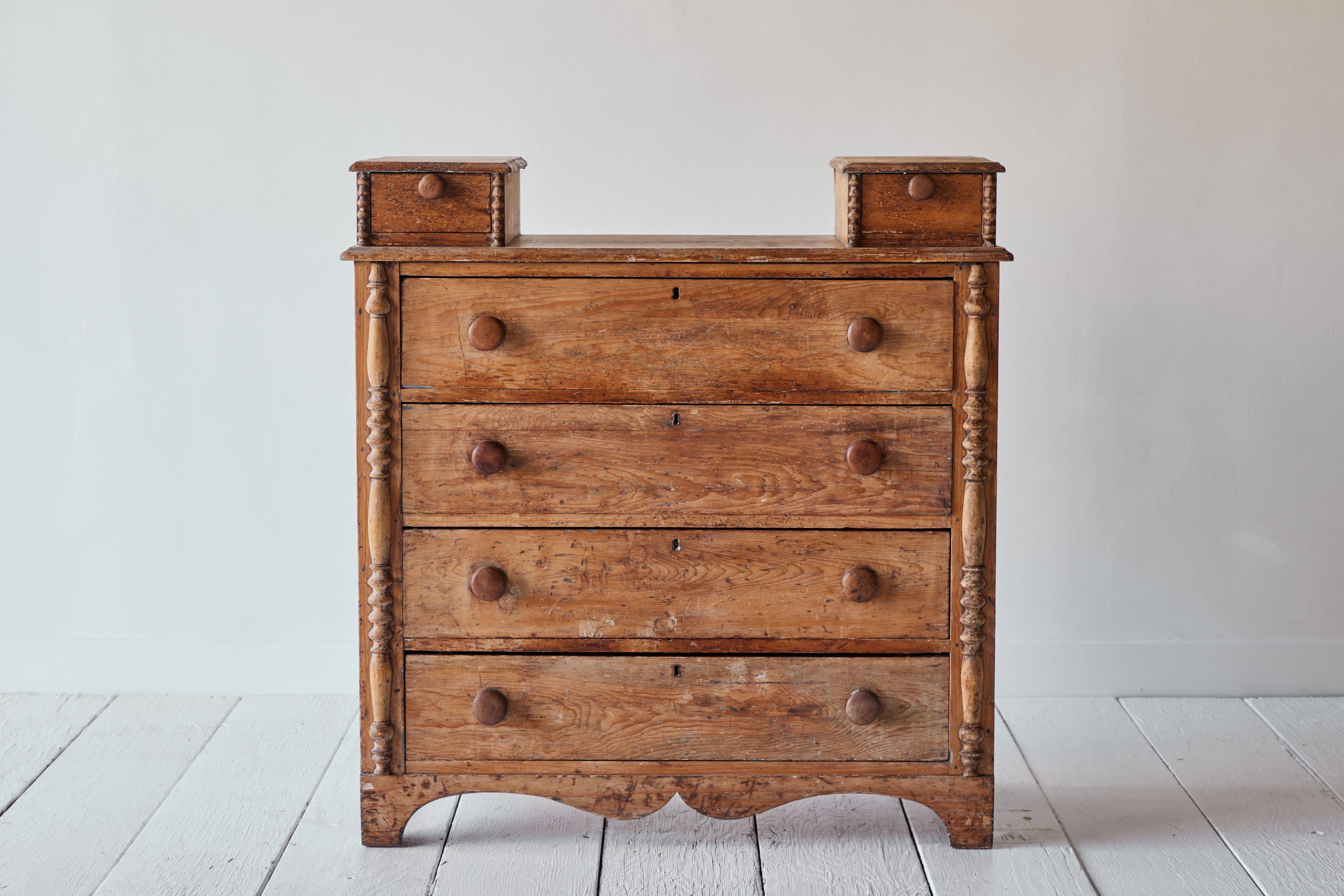 This 19th century English pine dresser features 4 large drawers with two smaller drawers that sit on either side of the top of the dresser. The beautiful spool detail makes this dresser an extra special piece. The dresser has a charming patina that
