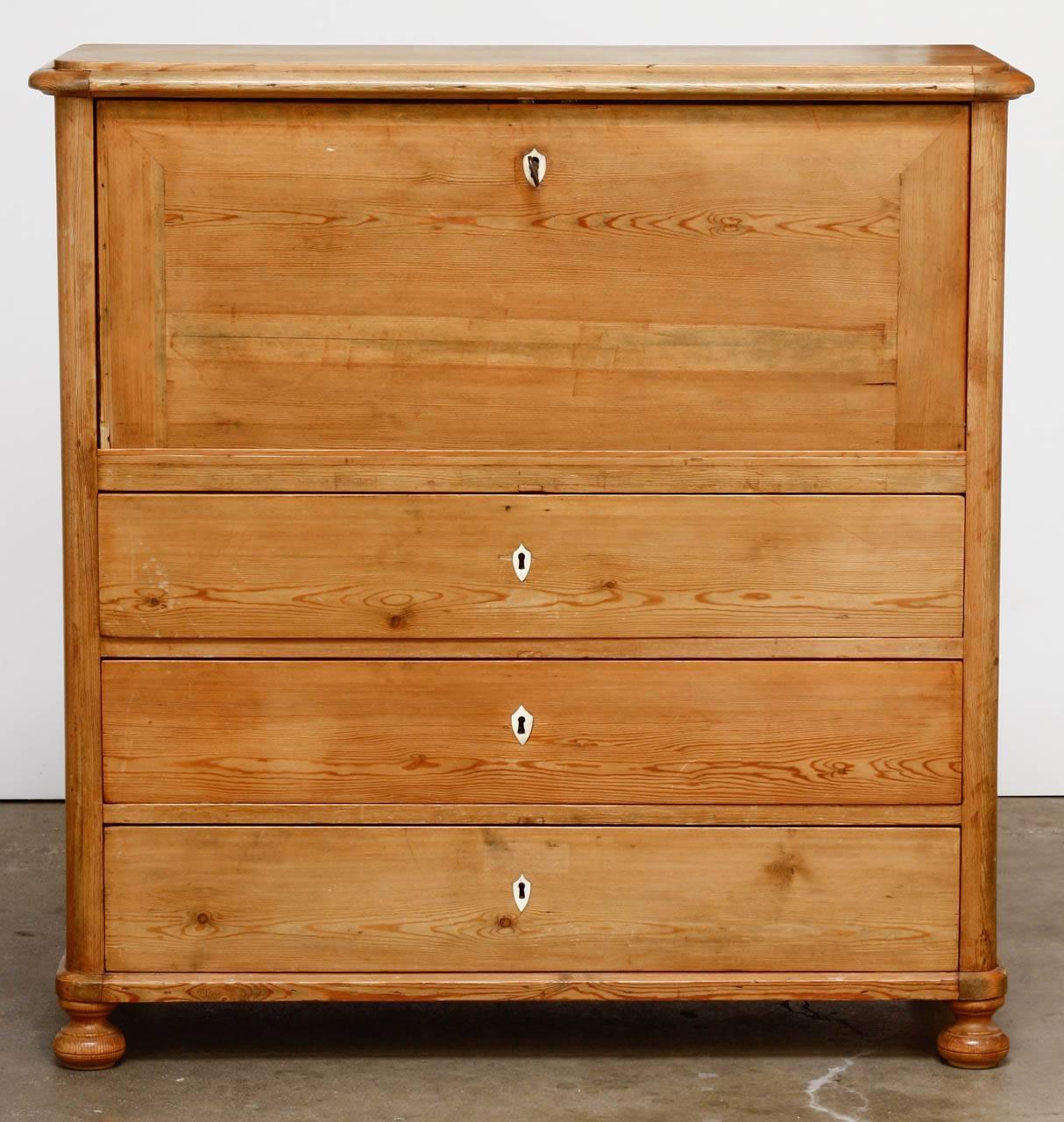 Grand 19th century English pine secretary featuring a fall front or drop front writing surface. The desk is fitted with 13 storage drawers inside the interior with bird's eye maple fronts. There is also pigeon holes and a locking door with a bird's