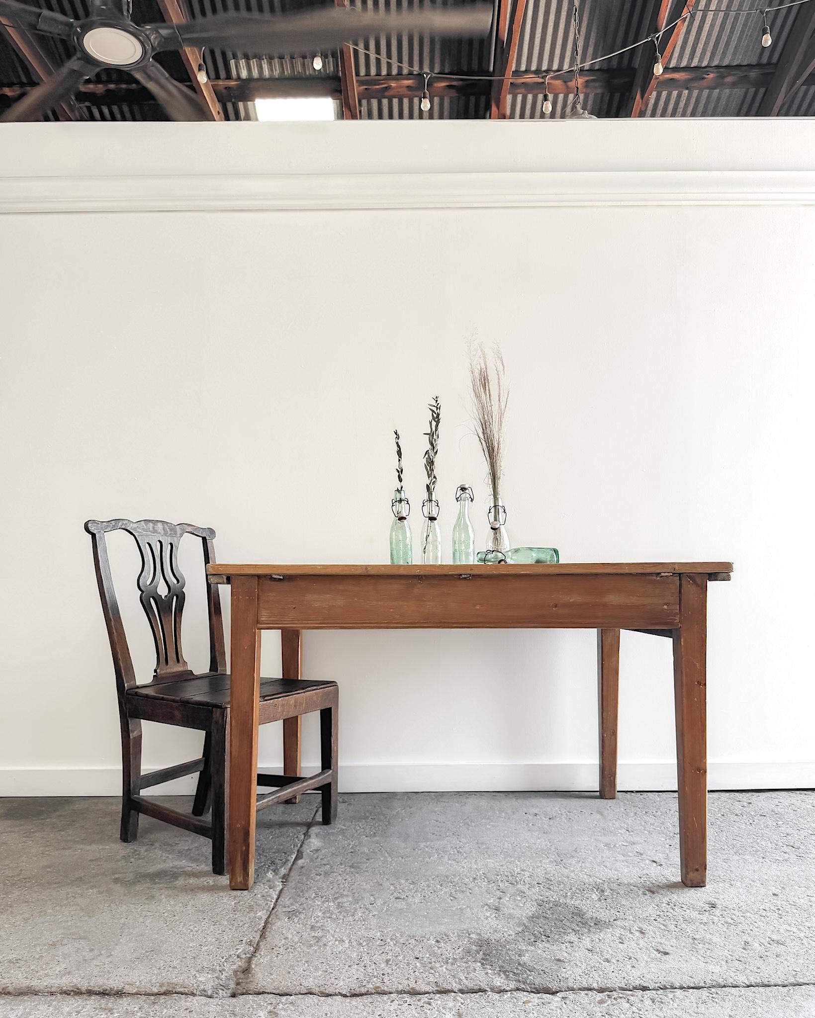 Crafted from solid pine, this small harvest kitchen table combines utility with a beautifully aged character. 

The planked top has a scrubbed, timeworn surface that showcases the natural patina of the wood, contrasting with the light honey-stained