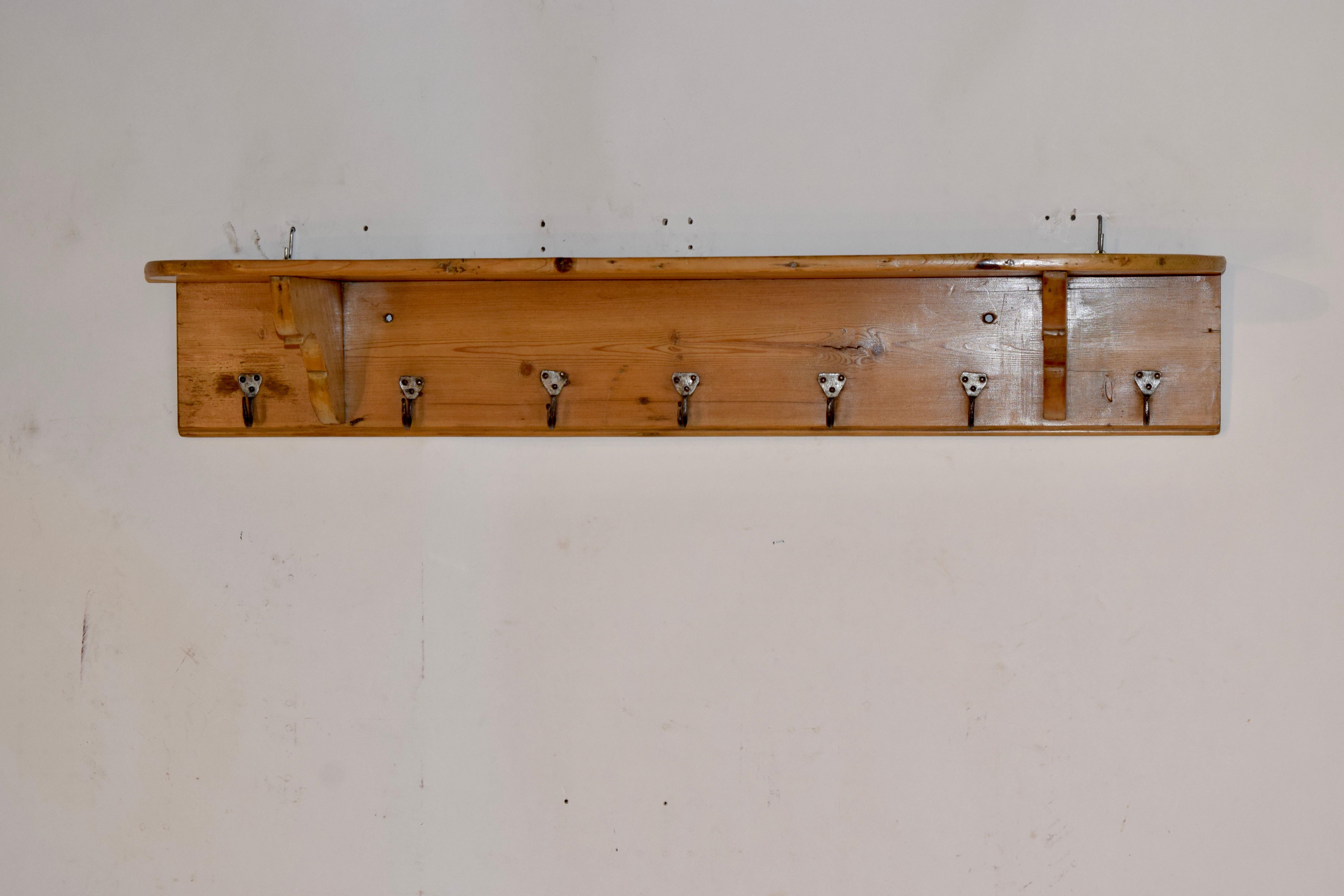 19th century pine wall shelf from England with serpentine support brackets and seven simple hat or coat hooks.