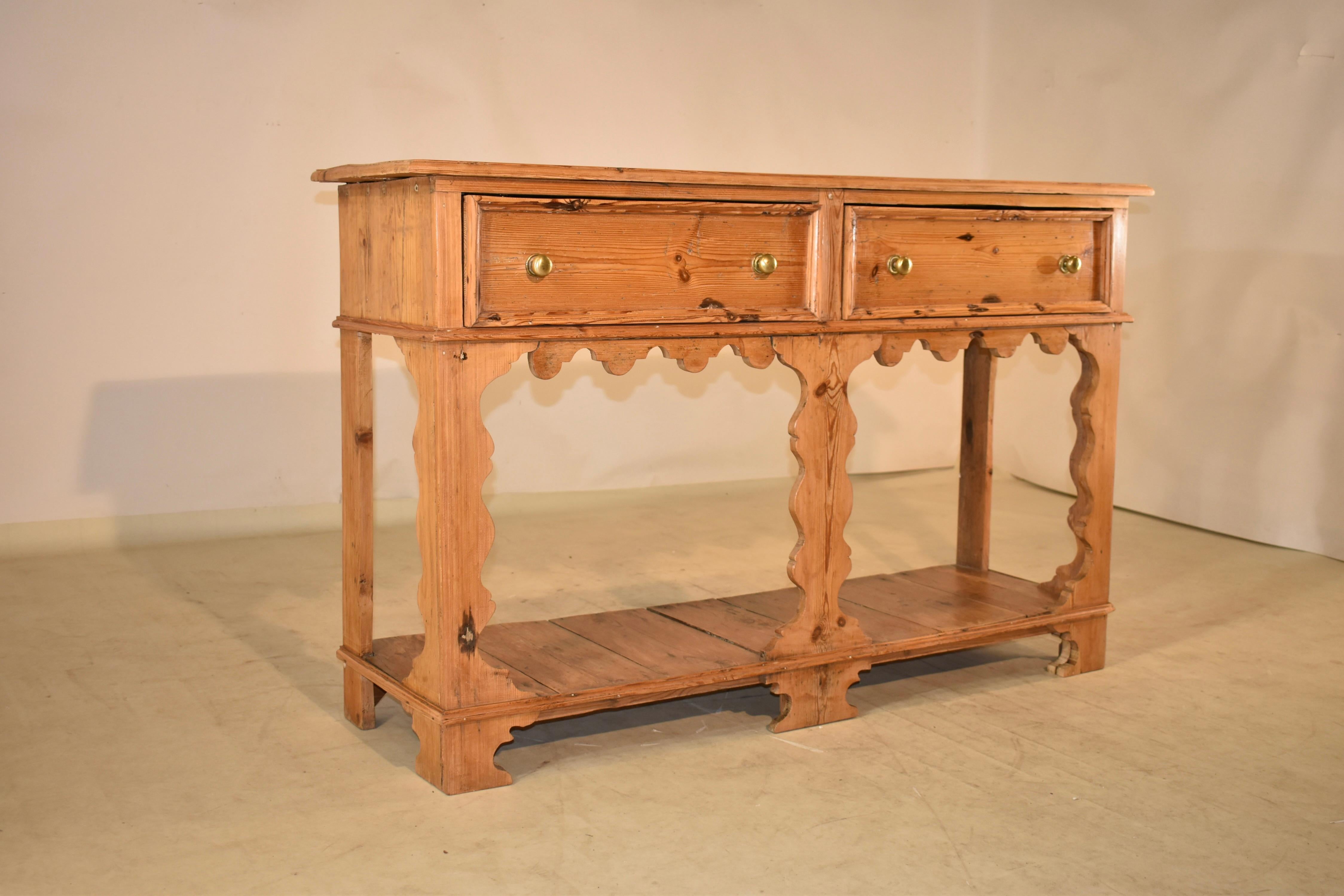19th century pine sideboard from England with a gorgeous plank top, following down to simple sides and two molded drawers in the front, over a wonderfully hand scalloped apron. The front legs and apron are hand scalloped, for lovely cottage design