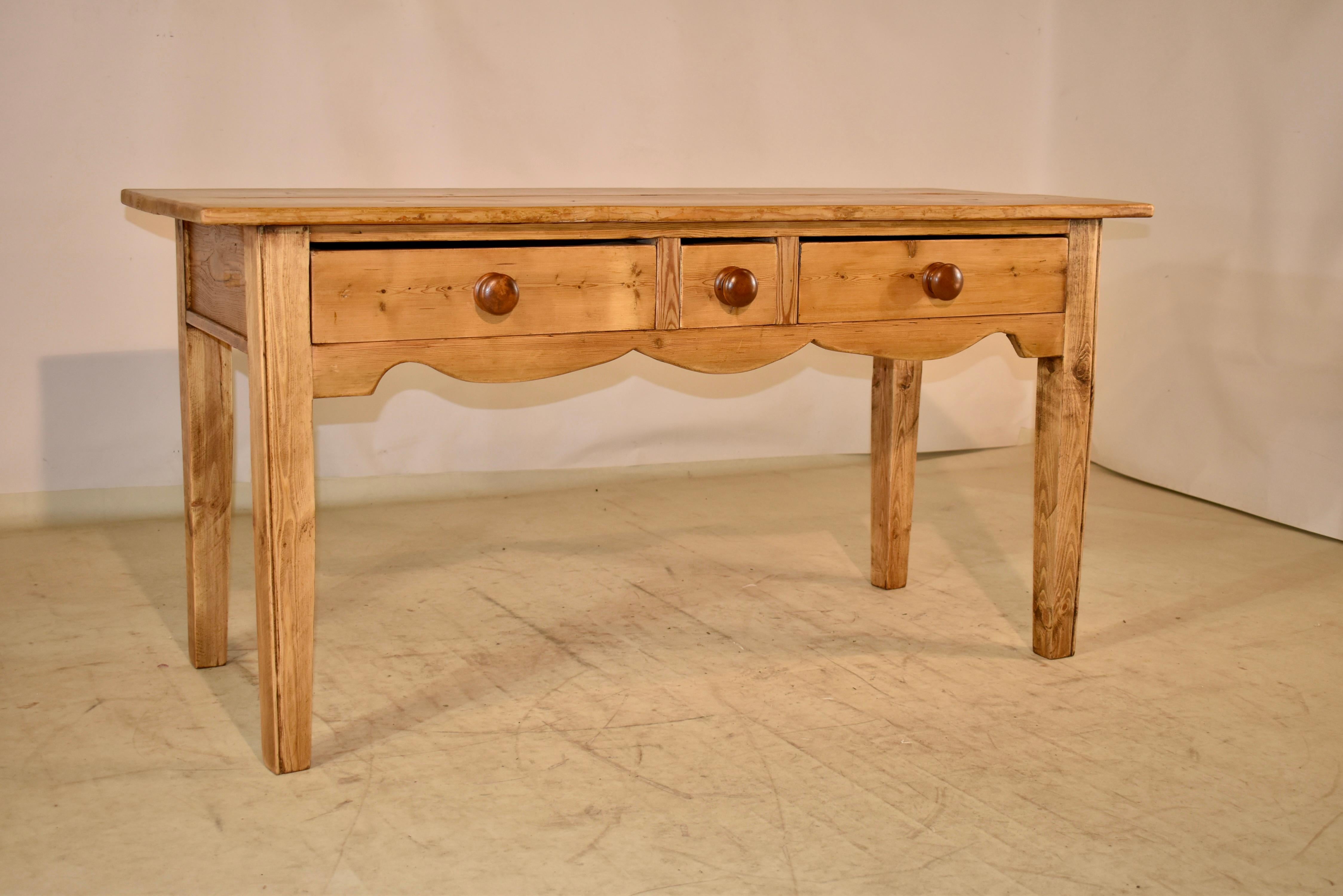 19th century pine sideboard from England with a two plank top over simple sides and three drawers in the front. There is a scalloped apron beneath the drawers and the piece is raised on simple tapered legs. This is a great piece with lots of