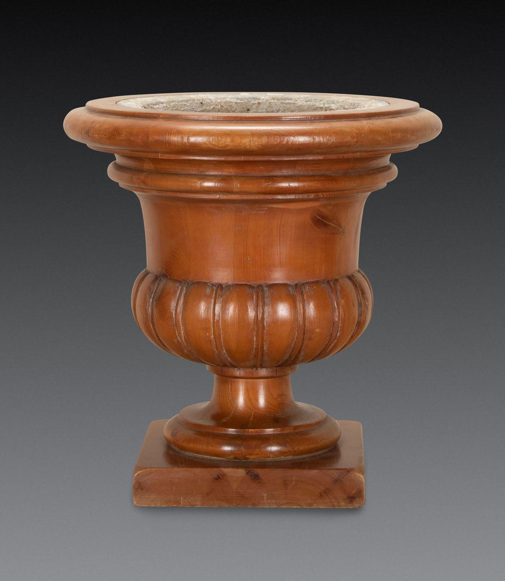 Urna clásica de pino tallado del siglo XIX para enfriar vino/jardinera, de forma campana, con borde moldeado y cintura estriada, y elevada sobre base de plinto, con forro de hojalata. Alrededor de 1880. En buen estado, lista para usar. La base de 26